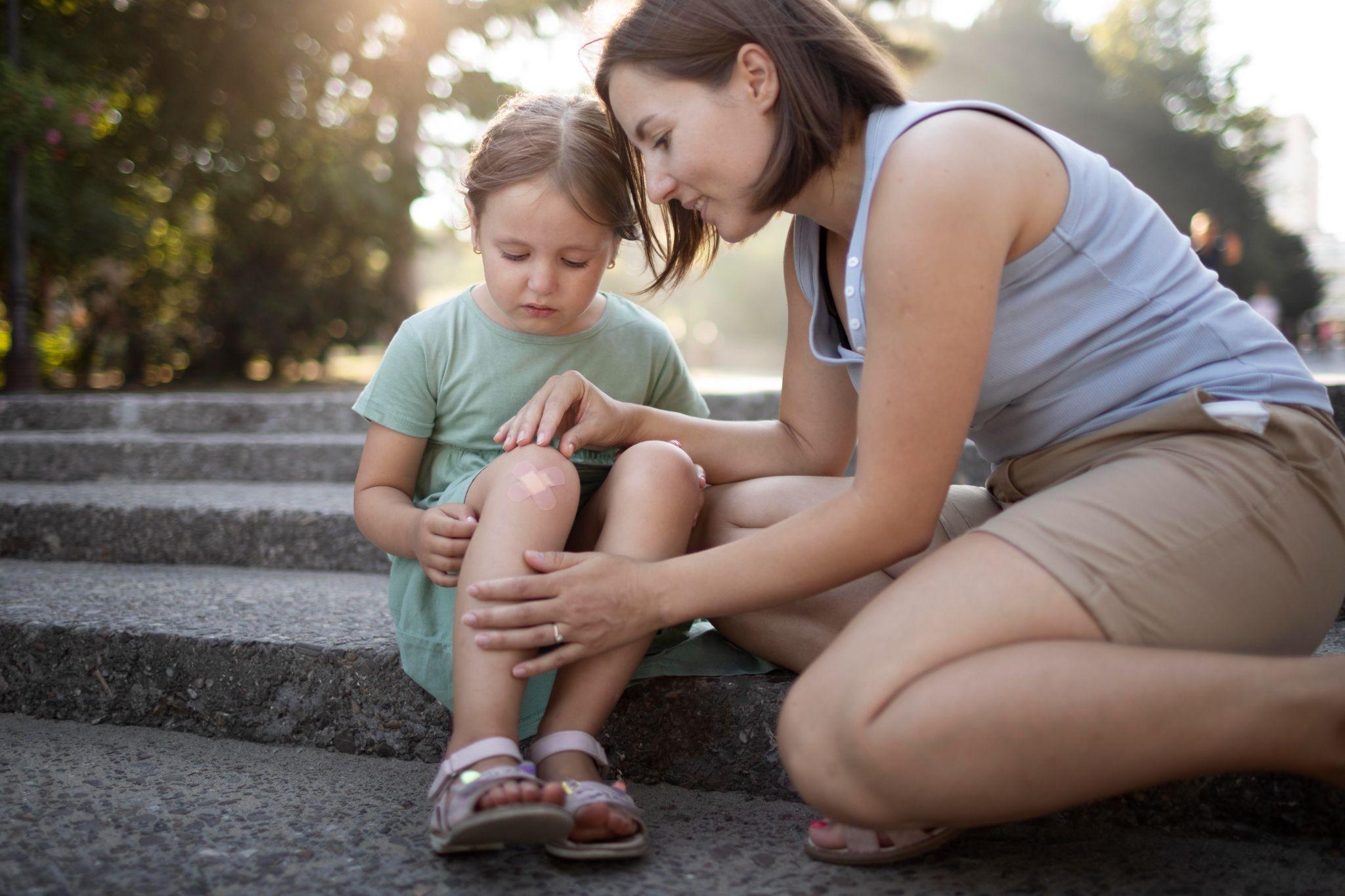 A parent caring for a child’s minor knee injury after outdoor play.