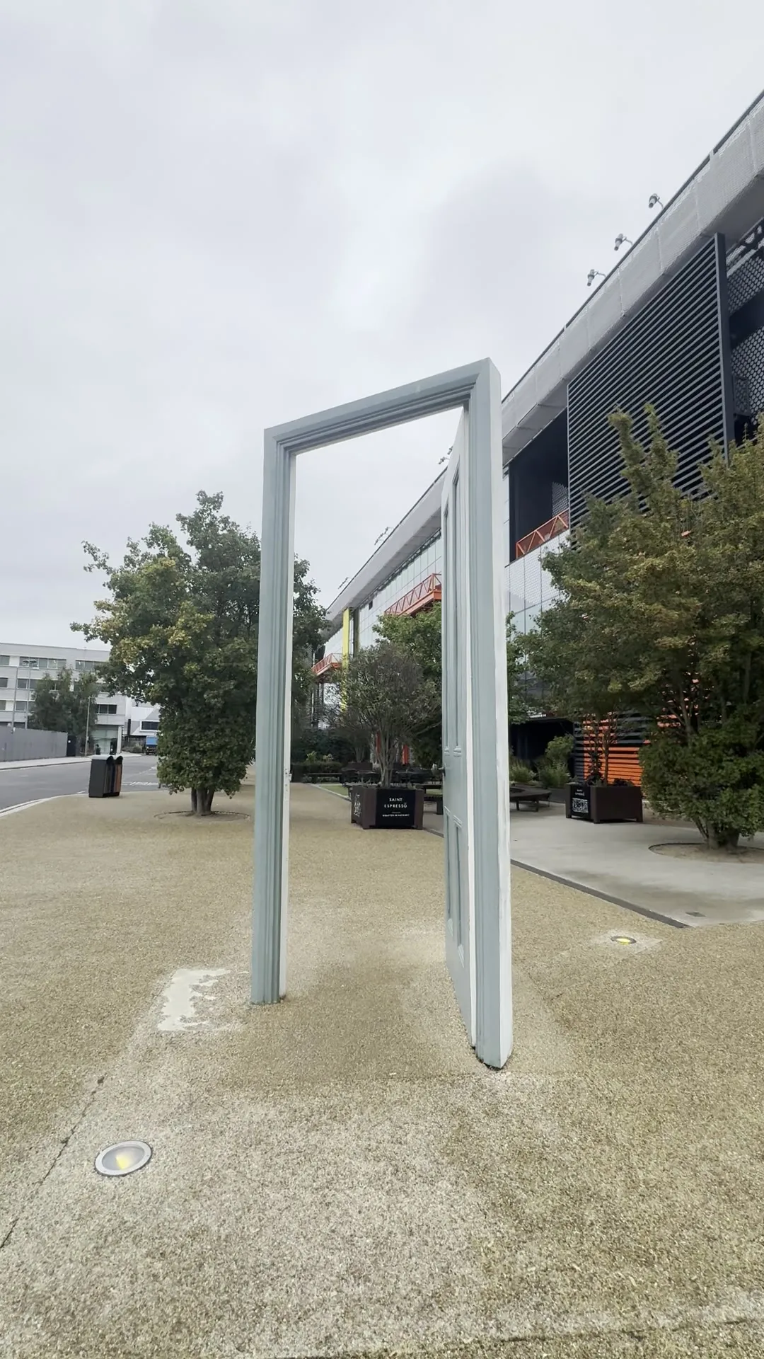 A free-standing sculpture of an open door and frame on the paving outside the creative campus in Stratford, East London