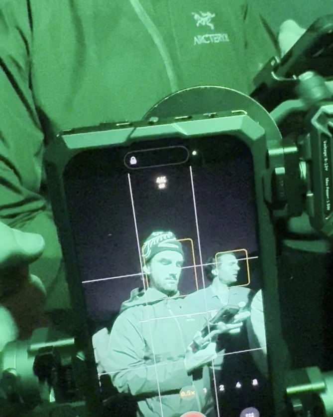 Close-up of the iPhone 18 Pro in a cage rig with side handles, its screen showing an actor framed for the shot