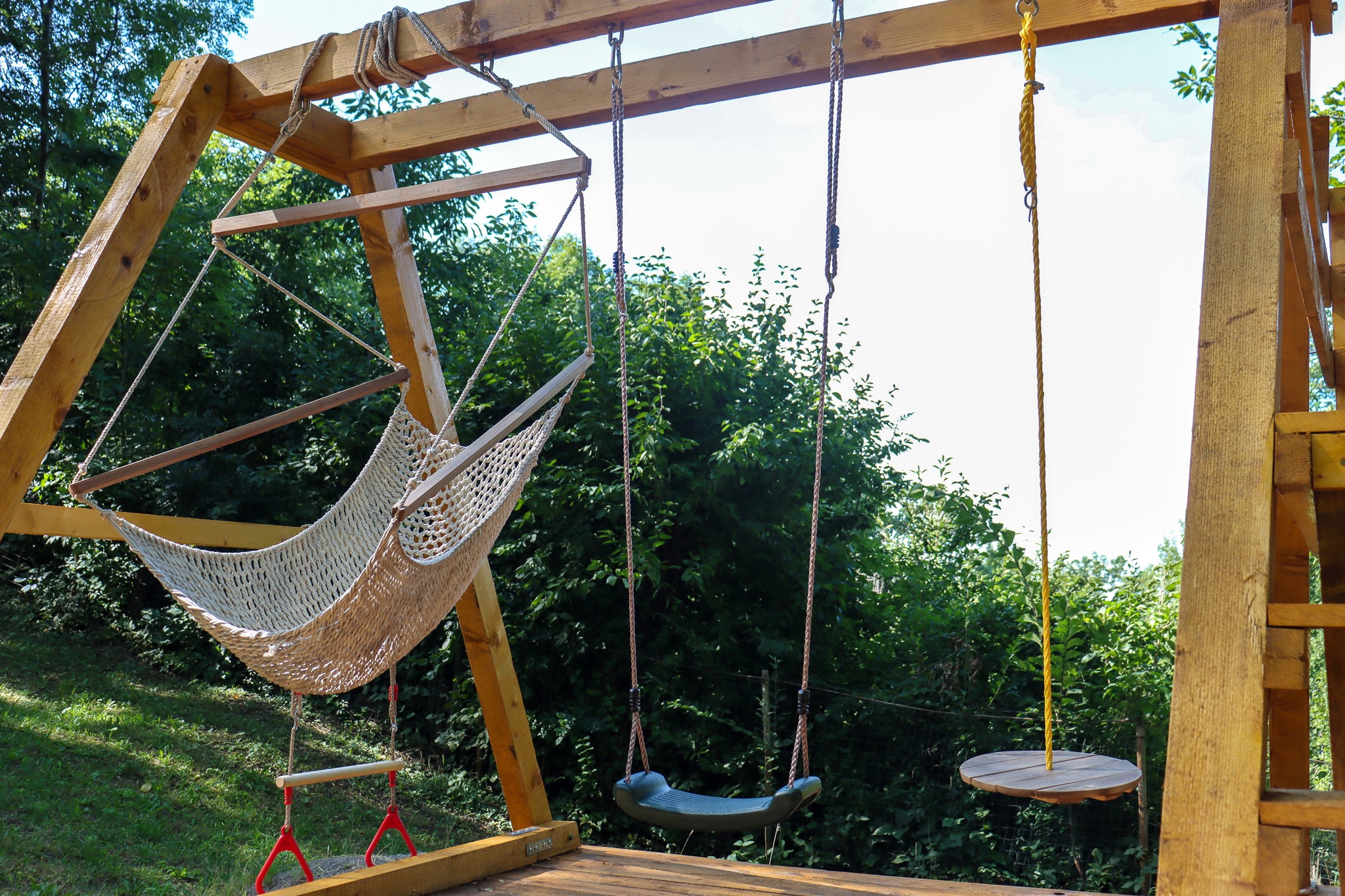 Wooden swing frame in the garden with forest backdrop