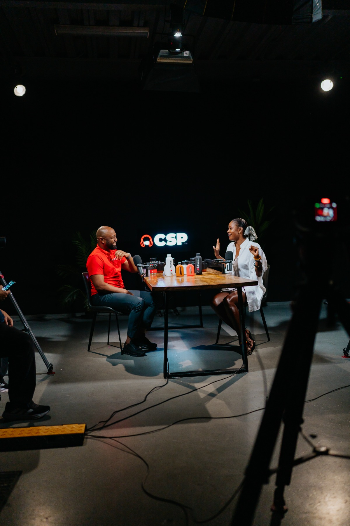 Two people recording a podcast at a table inside AI Studios