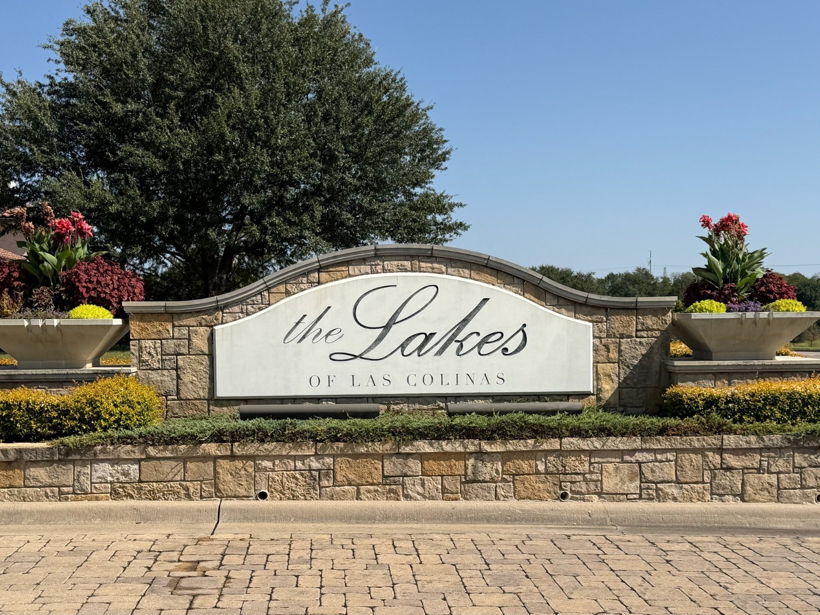 Golden-hour gated neighborhood arrival drive with manicured landscaping and mature trees