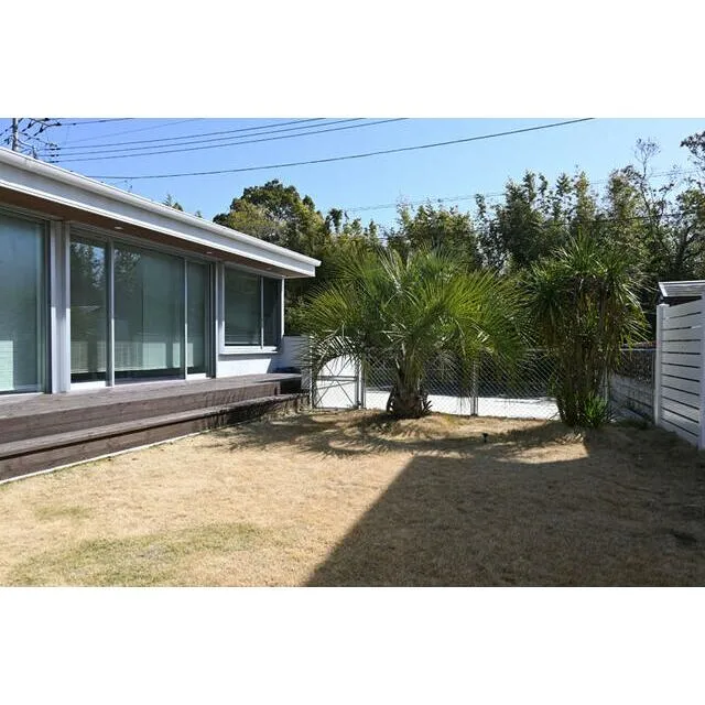 長生村一松中古戸建の広々とした庭とヤシの木のある外観