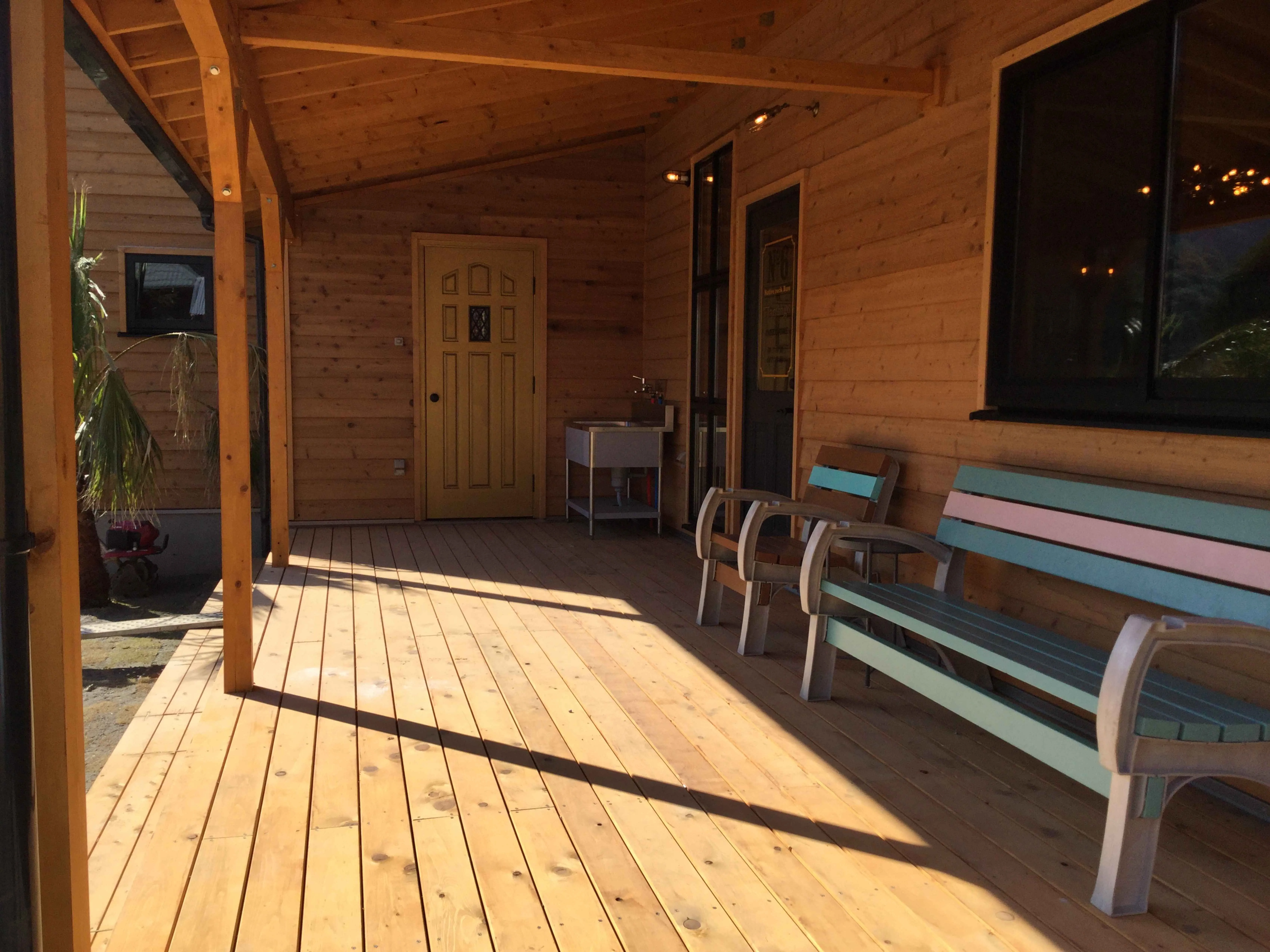 富津市岩本中古戸建の木製デッキテラス・カラフルなベンチが配置された屋根付きアウトドアスペース