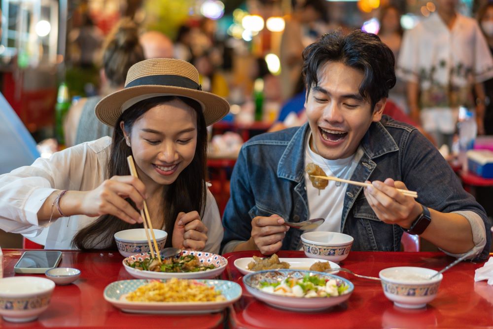 Friends sharing late night Thai street food in Bangkok 