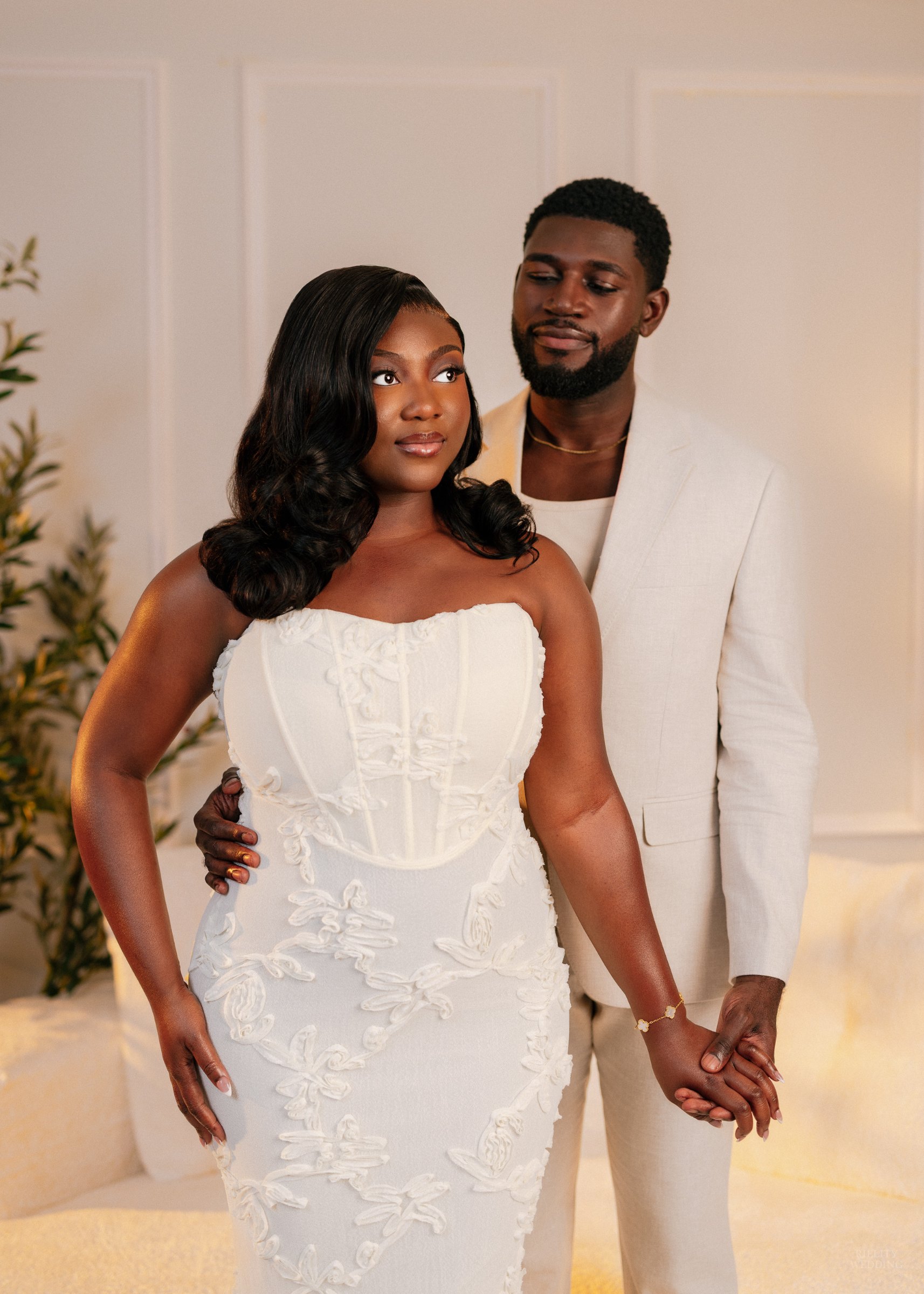 Engaged couple in cream outfits posing together in a bright studio for their engagement session