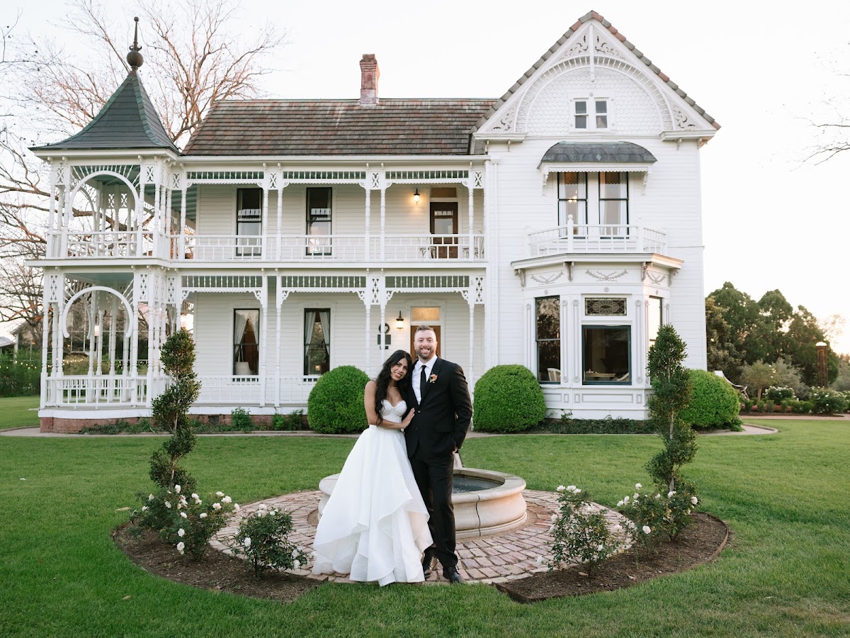 Barr Mansion, Austin — a couple in front of the white 1898 Victorian mansion and its gazebo
