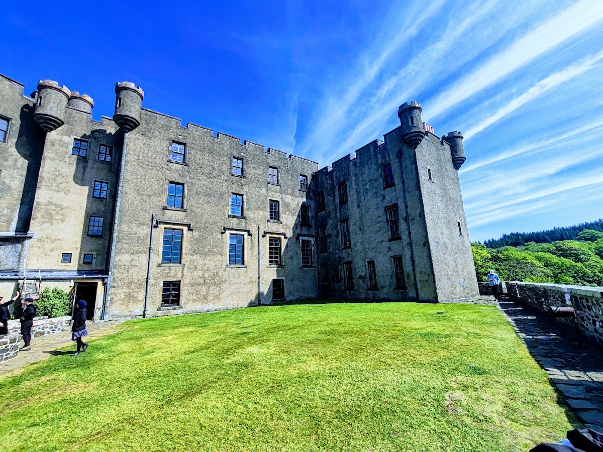 Dunvegan Castle, Isle of Skye — the grey stone castle above its lawn under a blue sky