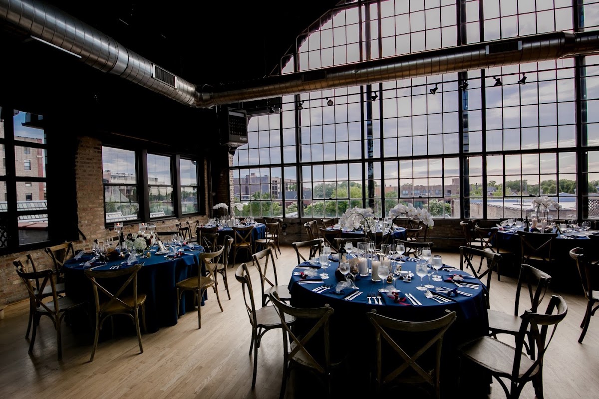 Ravenswood Event Center — reception tables under the industrial windows and timber beams of the showroom