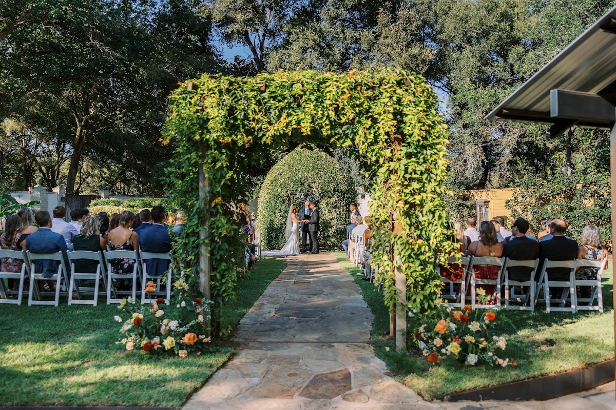 Hummingbird House, Manchaca — guests seated for a garden ceremony beneath a flower-covered arbor