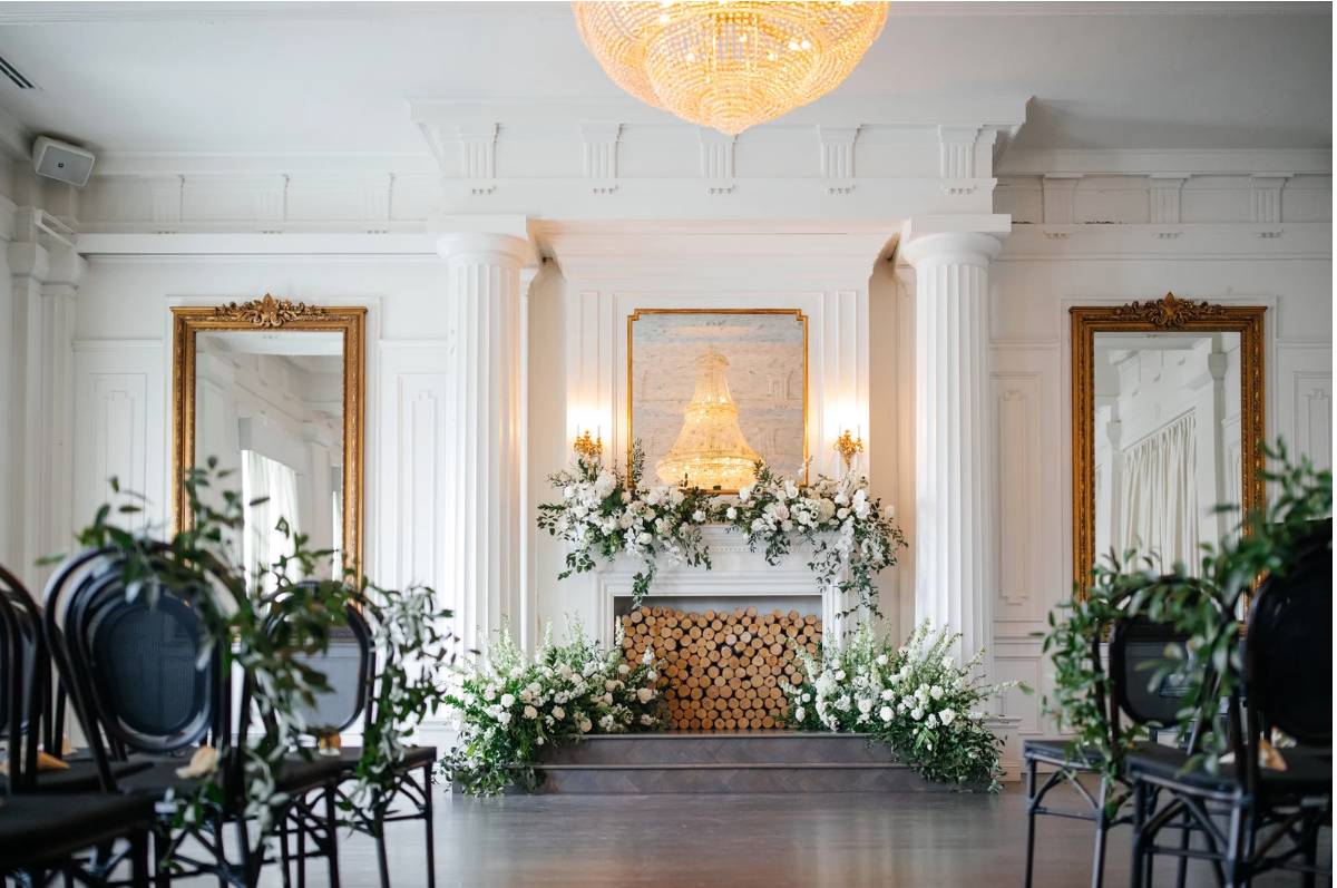 The Mason, Oak Cliff — a white-paneled room with a candlelit fireplace and chandelier