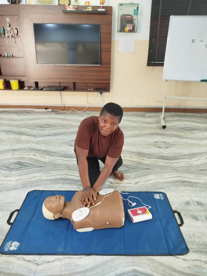 Student practising chest compressions with AED on CPR manikin