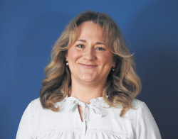 A smiling woman with a white top on stood in front of a dark blue background