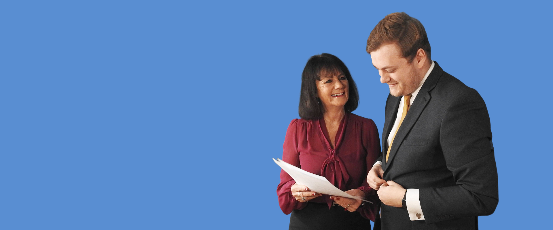Two advisers speaking over paperwork and sharing a laugh.