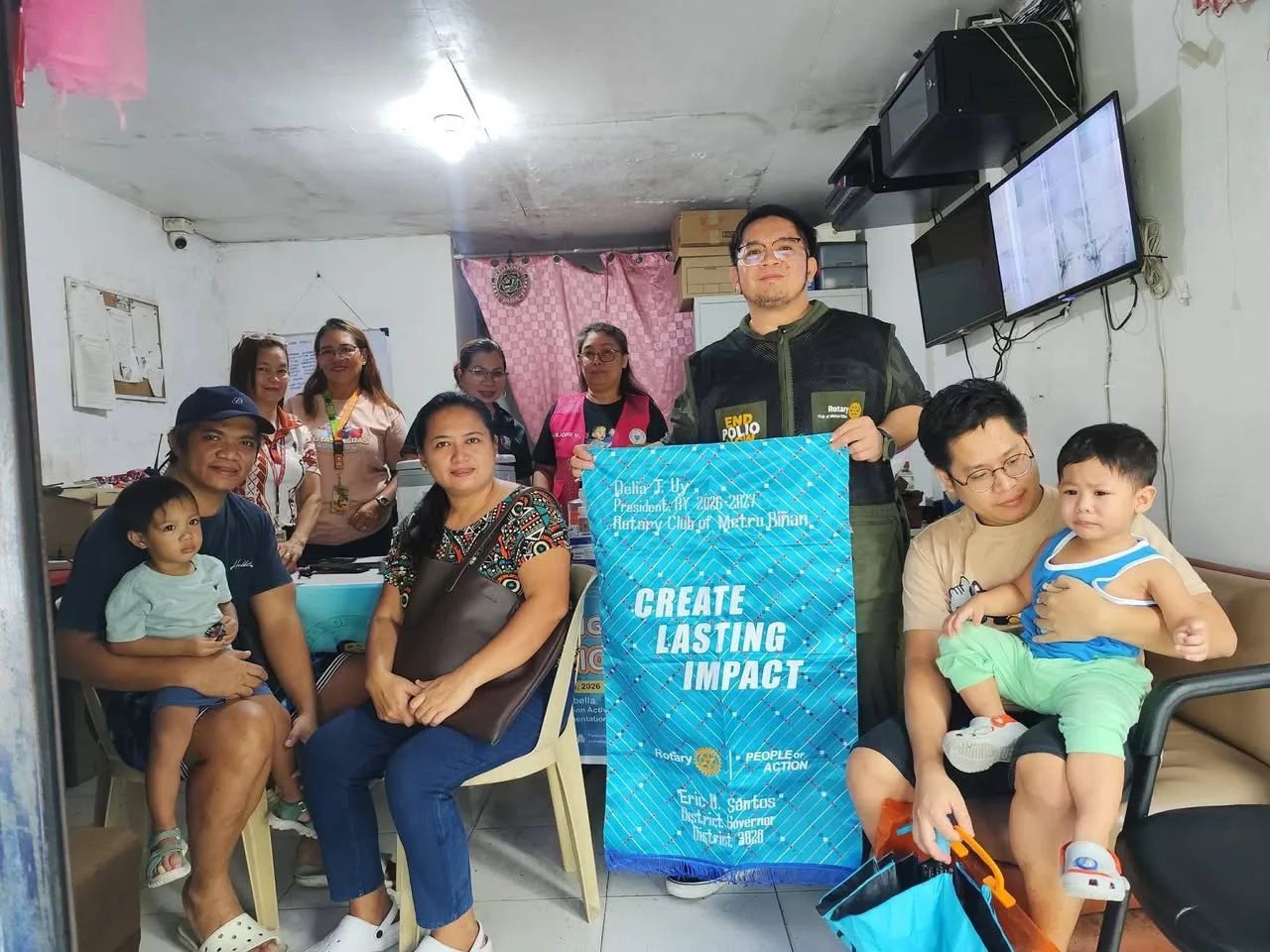 Rotary members and families gather with the club banner at the health center.