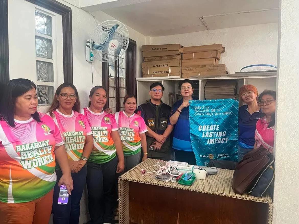 Rotary members and barangay health workers pose with the club banner at SV5 Health Center.