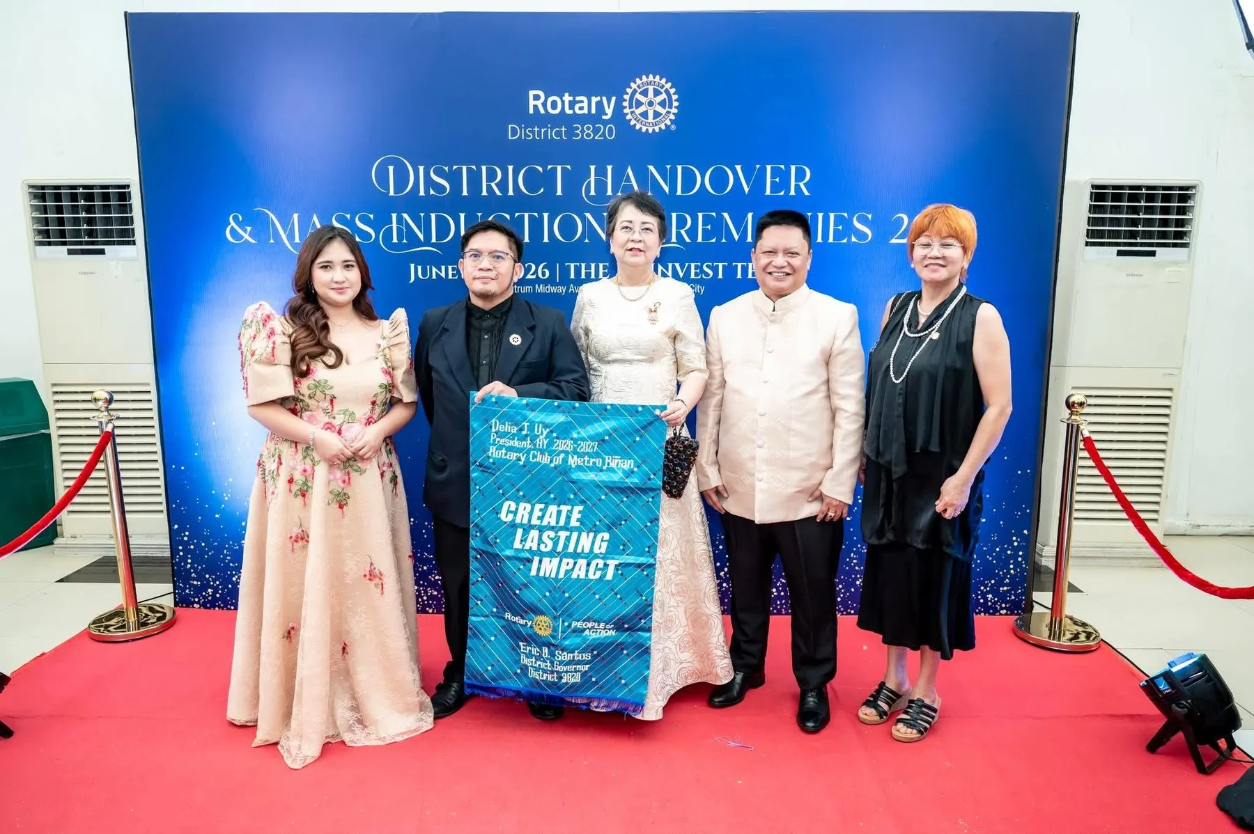 Rotary members pose with the club banner at the district handover and mass induction ceremony.