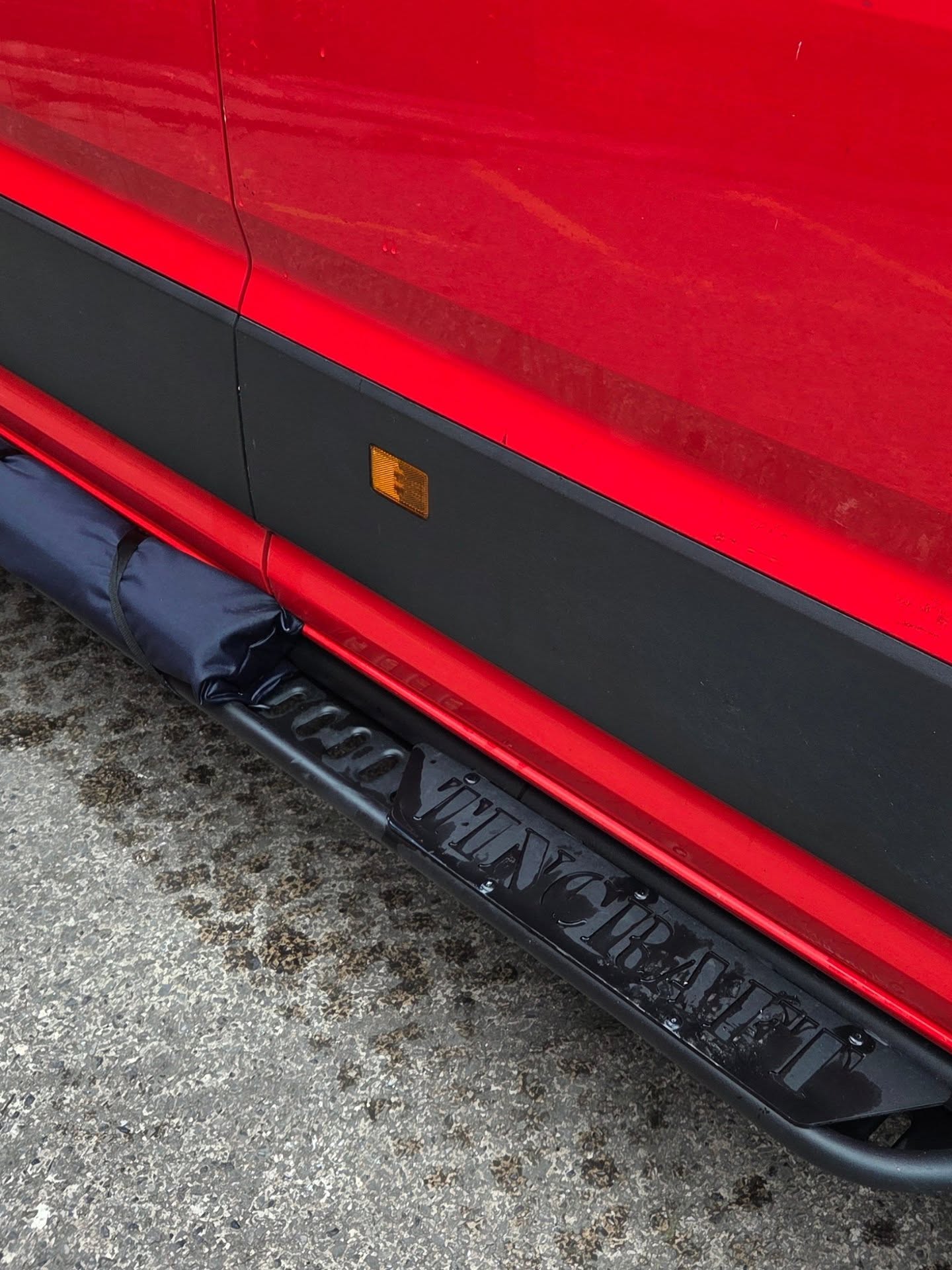 Tincraft name cut into the side step bar of a red VW Crafter camper conversion