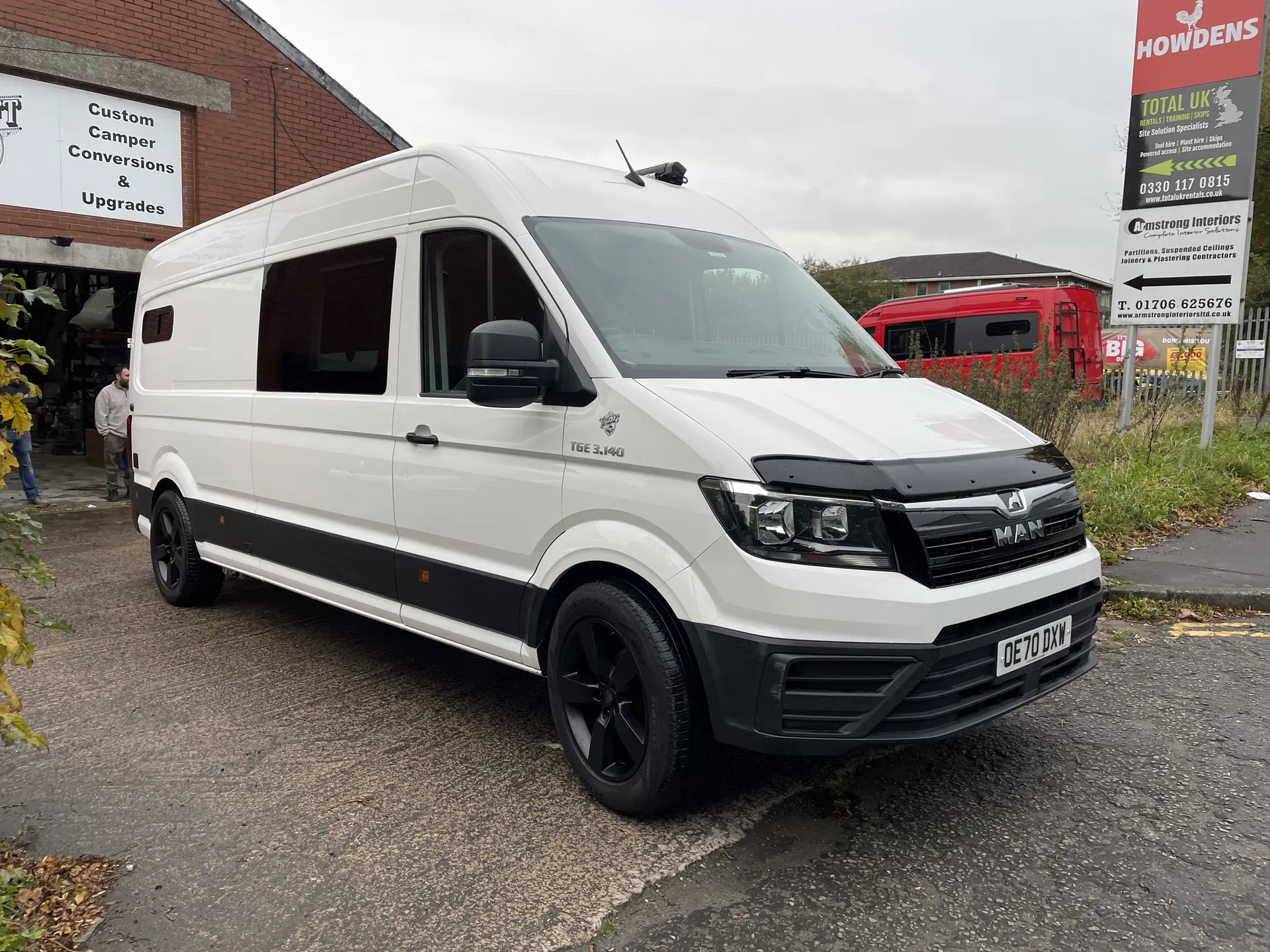 White MAN TGE campervan conversion on a road, front three-quarter view with black alloy wheels