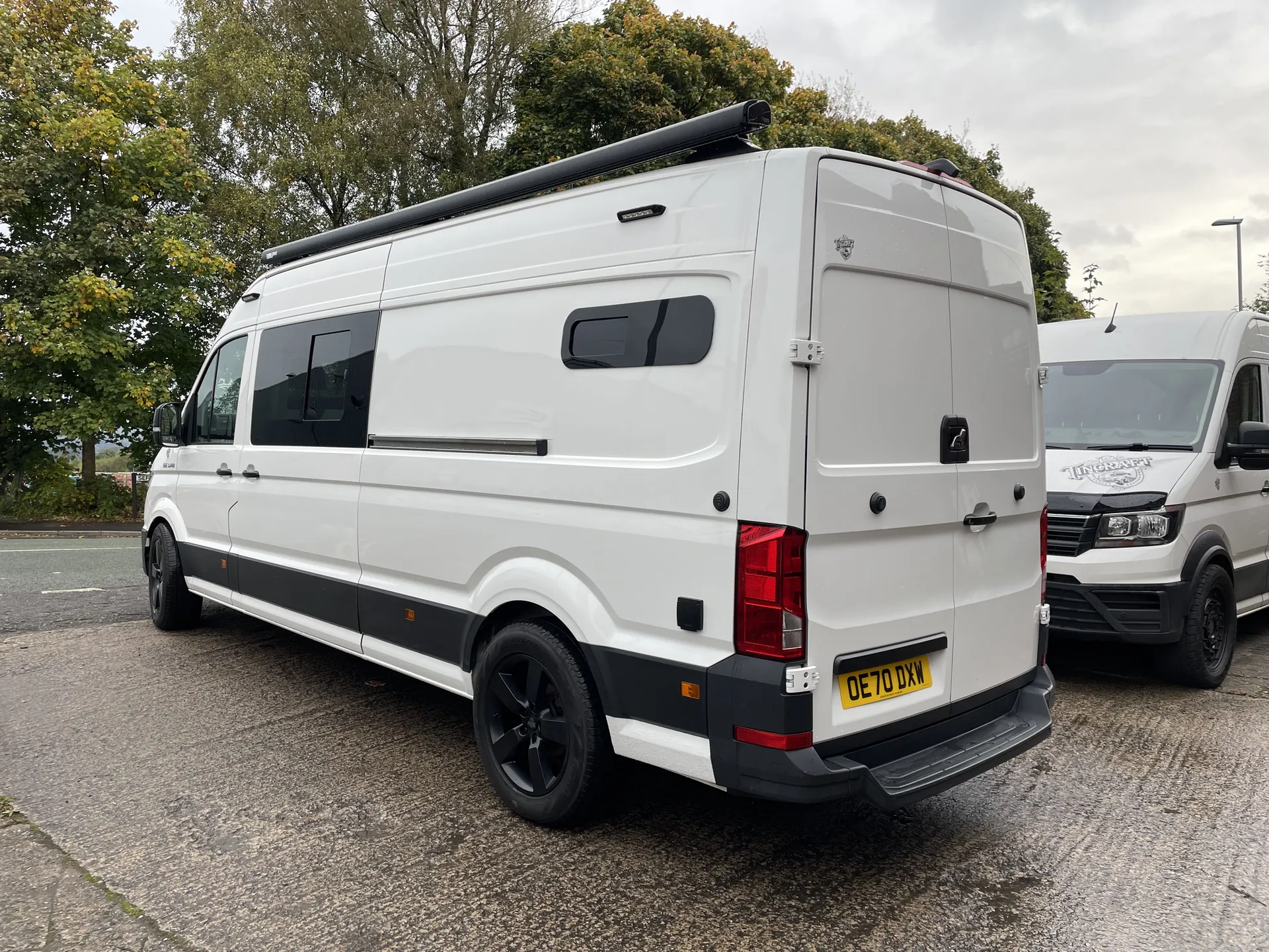 Rear three-quarter view of a white MAN TGE camper conversion with a low-profile roof rack