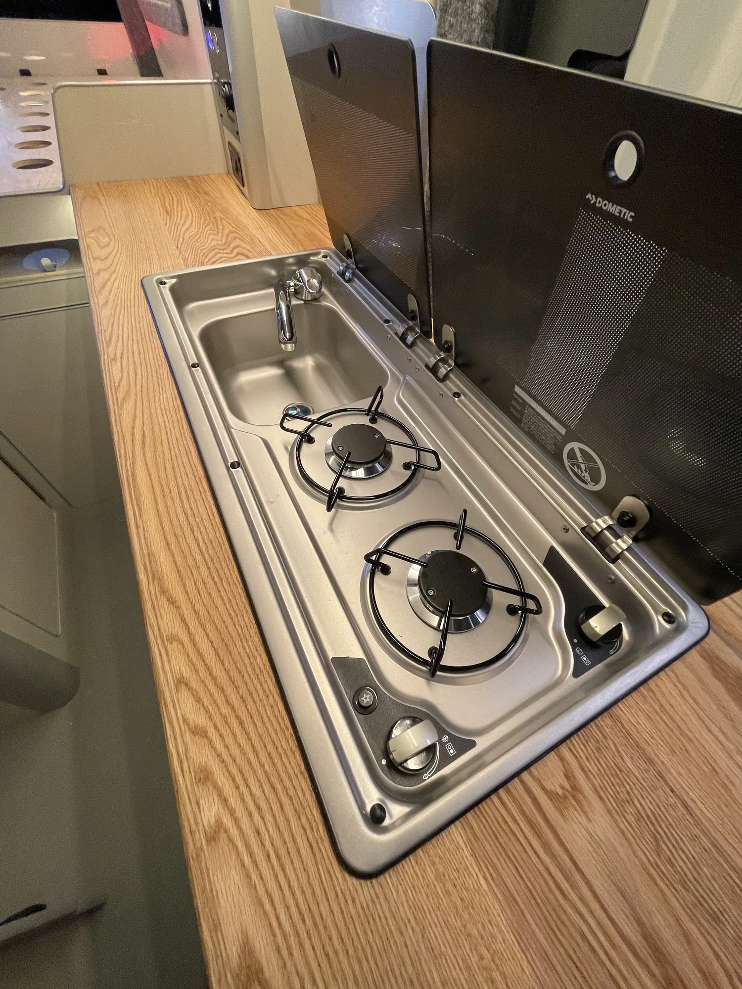 Hob and stainless sink set into an oak worktop in a MAN TGE campervan galley