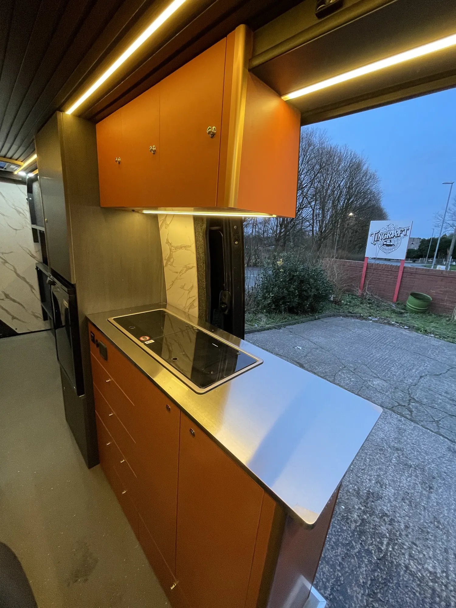 Worktop and hob below copper overhead lockers in a Mercedes Sprinter conversion