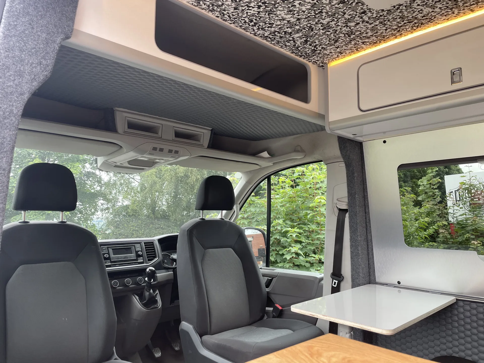 Swivelled cab seats facing a dining table in a VW Crafter conversion