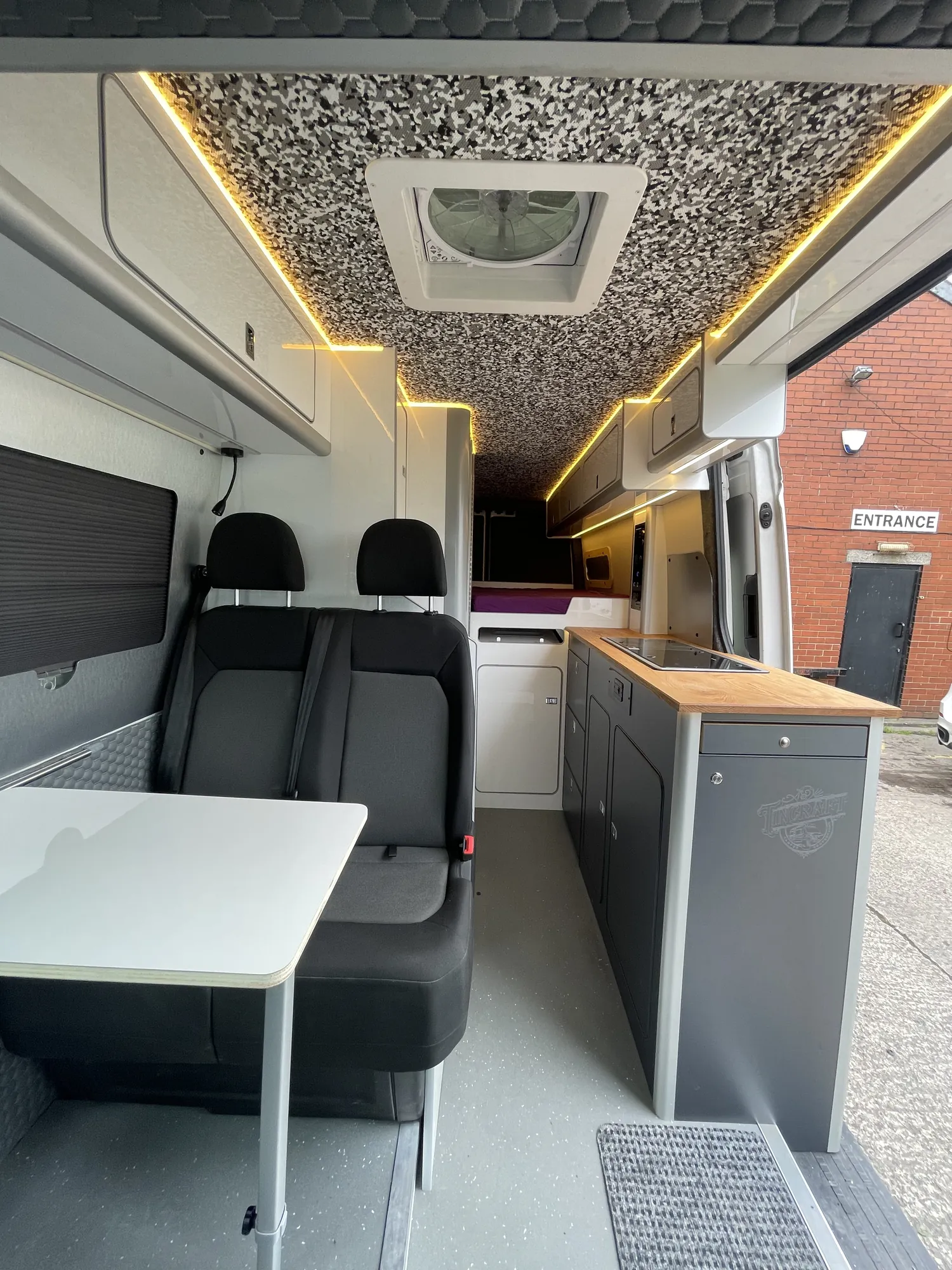 Dinette with the table set up and grey upholstery in a VW Crafter campervan