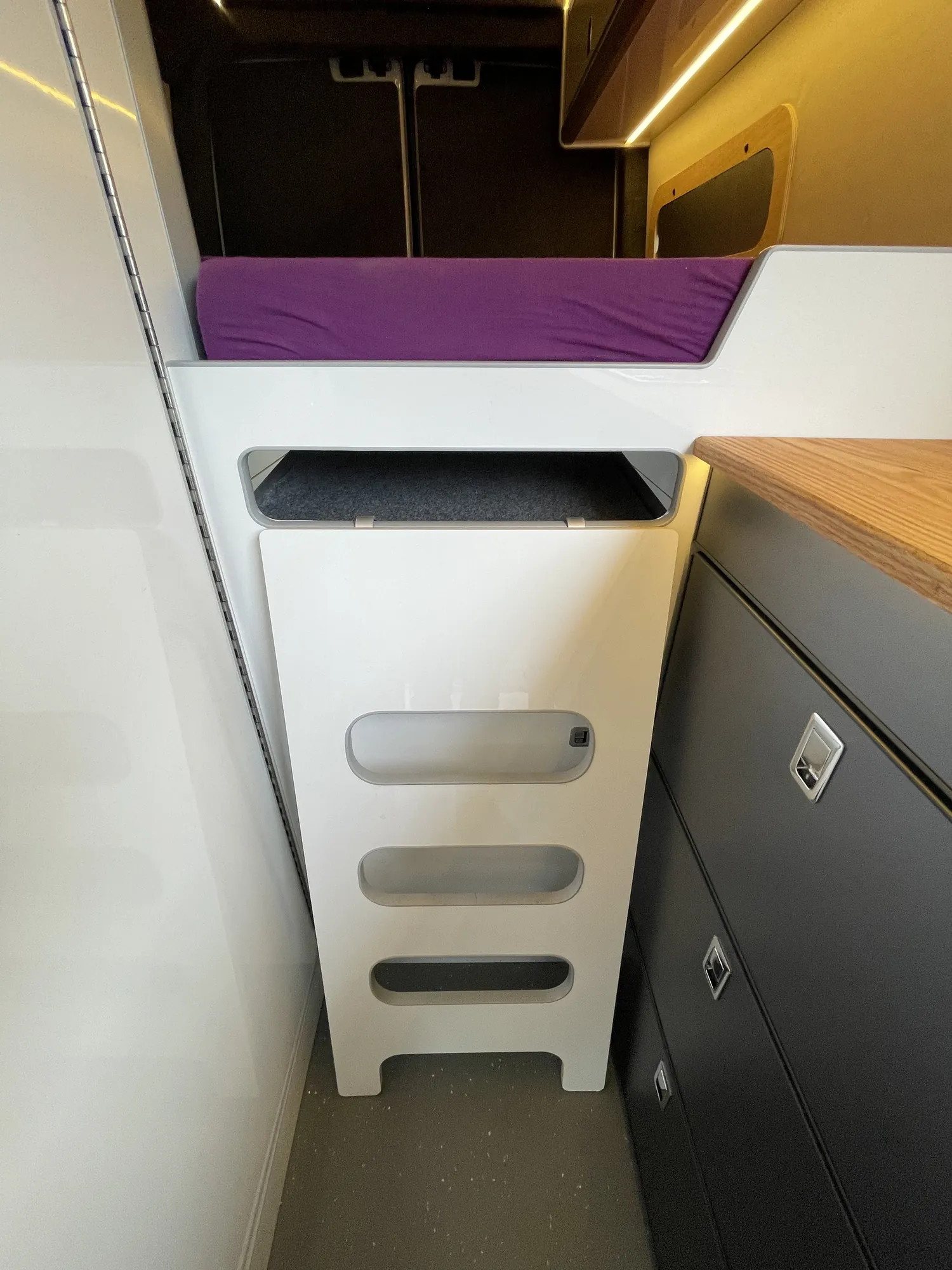 Steps up to the bed with built-in storage in a VW Crafter campervan