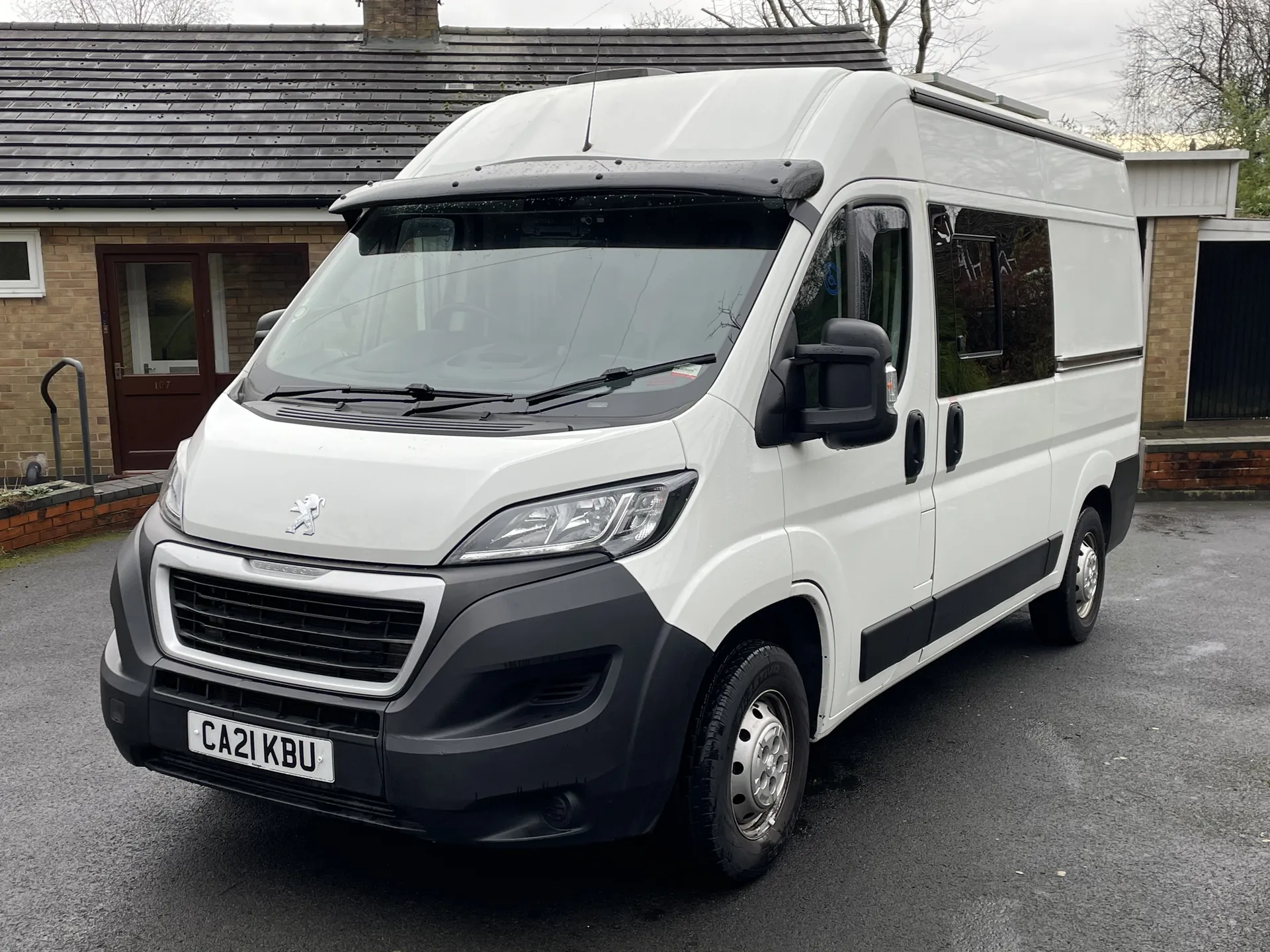 White Peugeot Boxer campervan conversion, front three-quarter view on a driveway