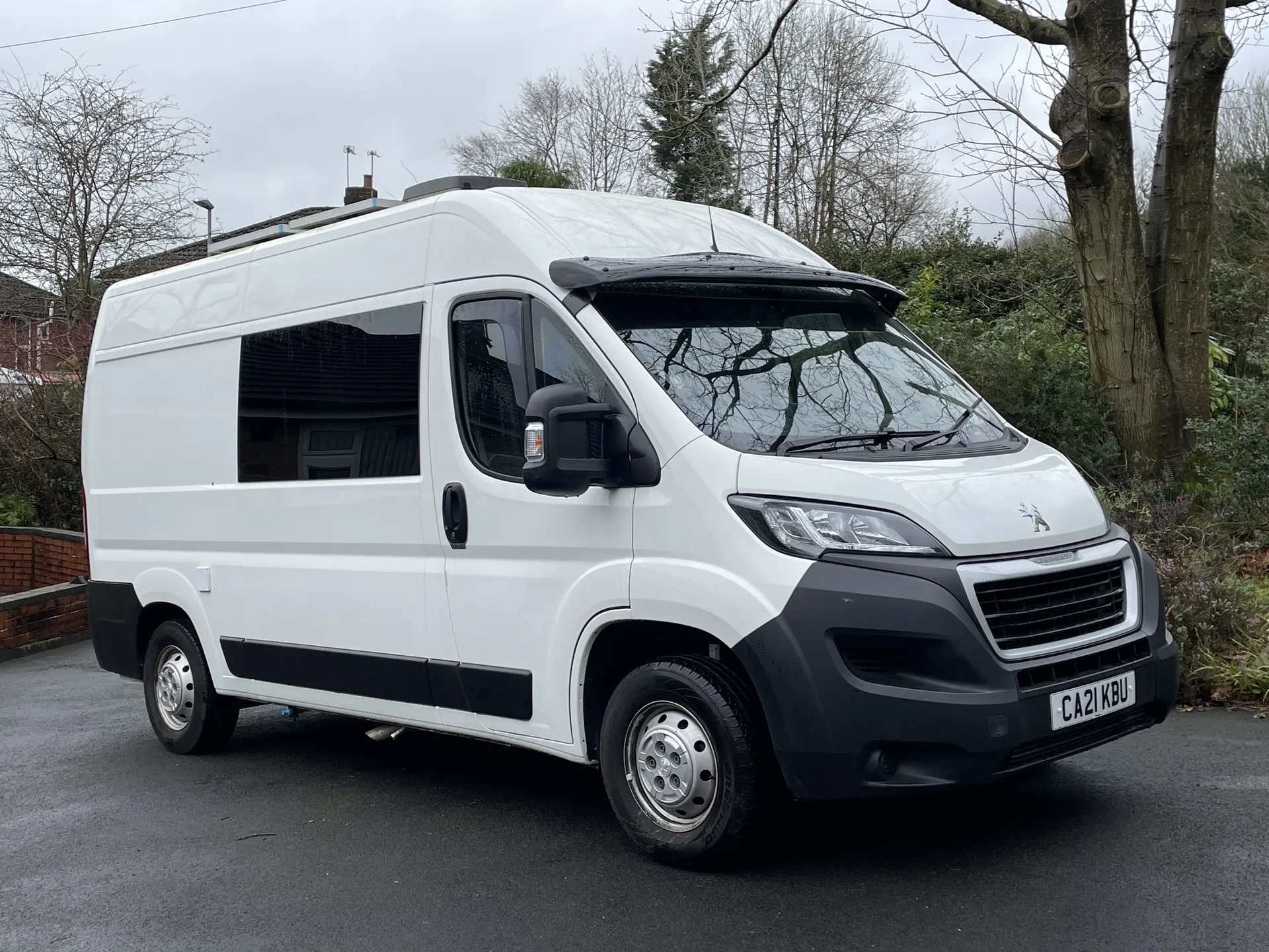 White Peugeot Boxer camper conversion photographed from the front on a road