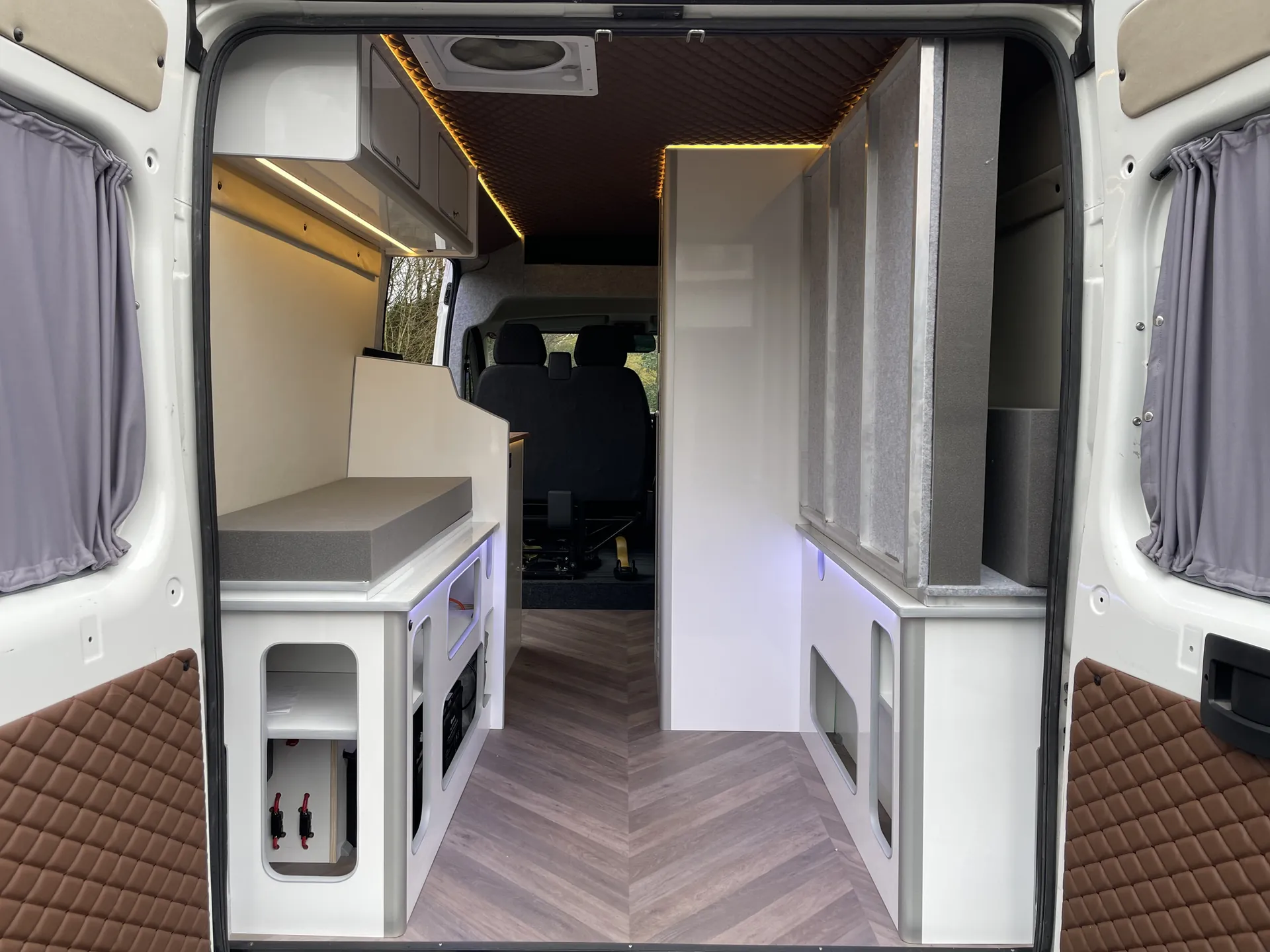 Peugeot Boxer camper interior from the rear, showing the galley and herringbone floor