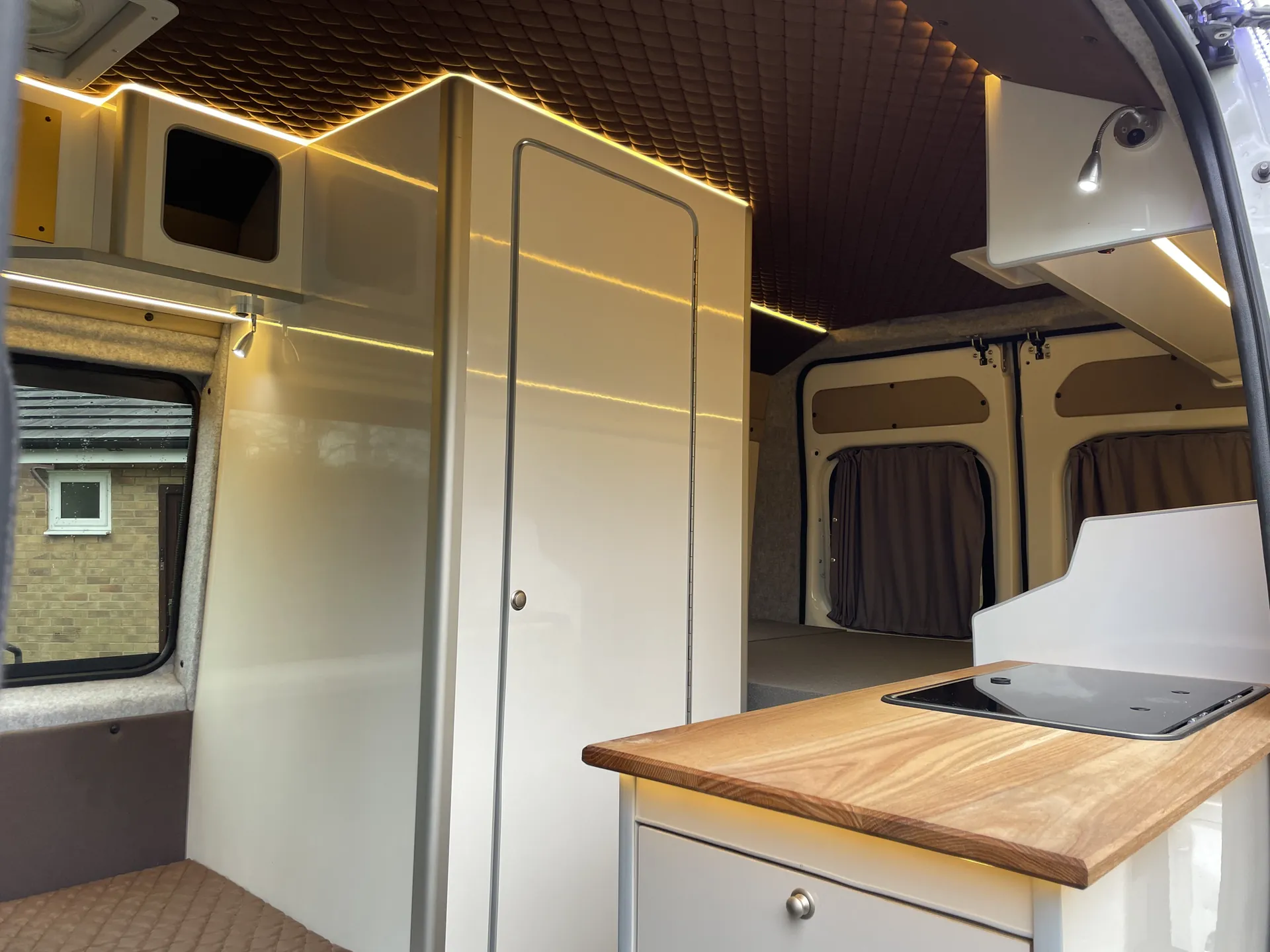 Oak worktop against cream gloss units in a Peugeot Boxer campervan galley