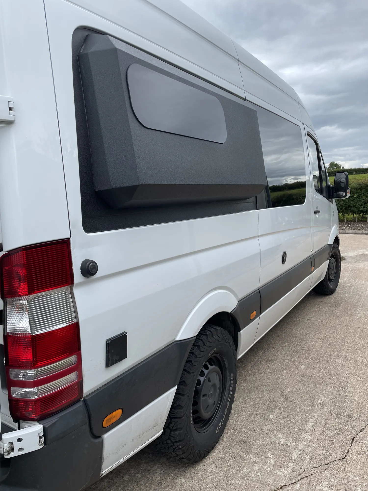 Side profile of a white Sprinter conversion with a grey moulded storage pod
