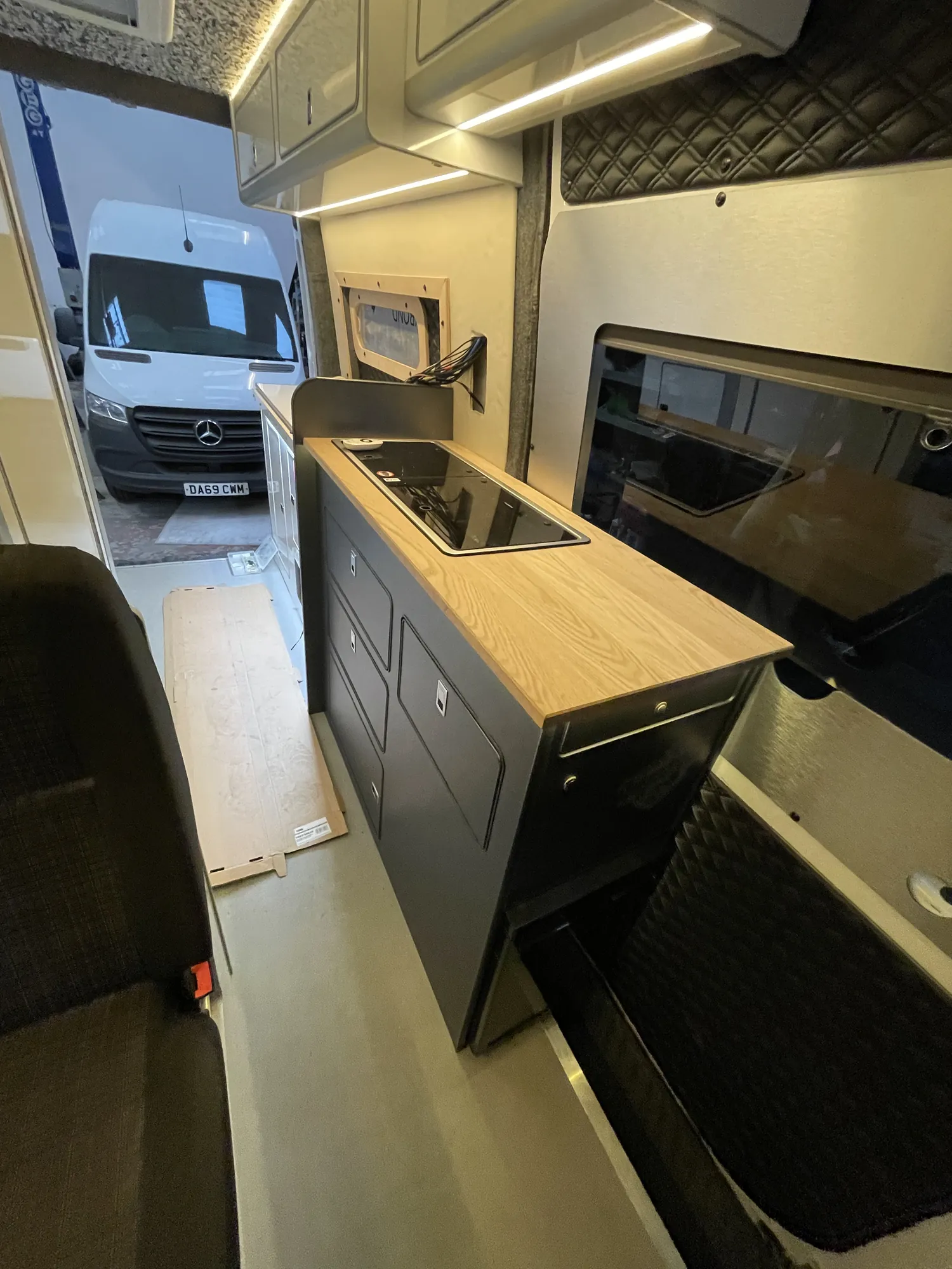Oak worktop and hob set in grey units in a Mercedes Sprinter camper galley