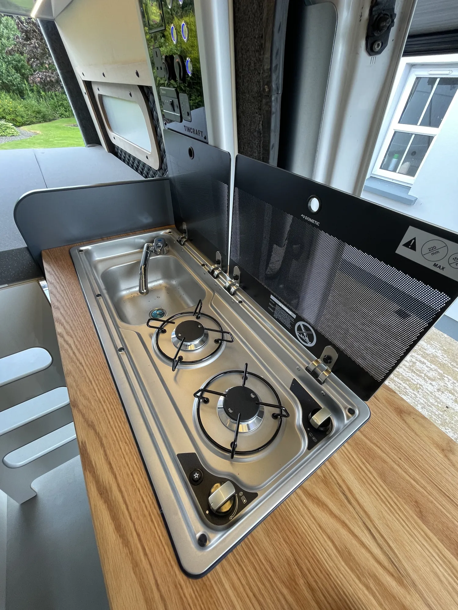 Hob with the glass lid raised on an oak worktop in a Sprinter conversion