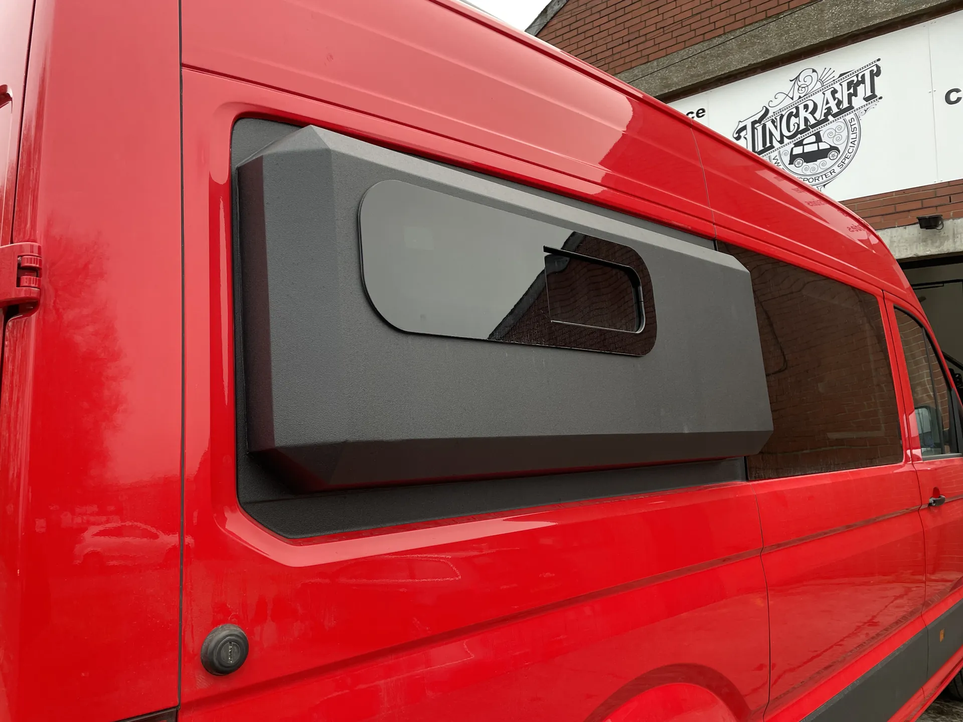 Grey moulded storage pod mounted on the side of a red VW Crafter camper