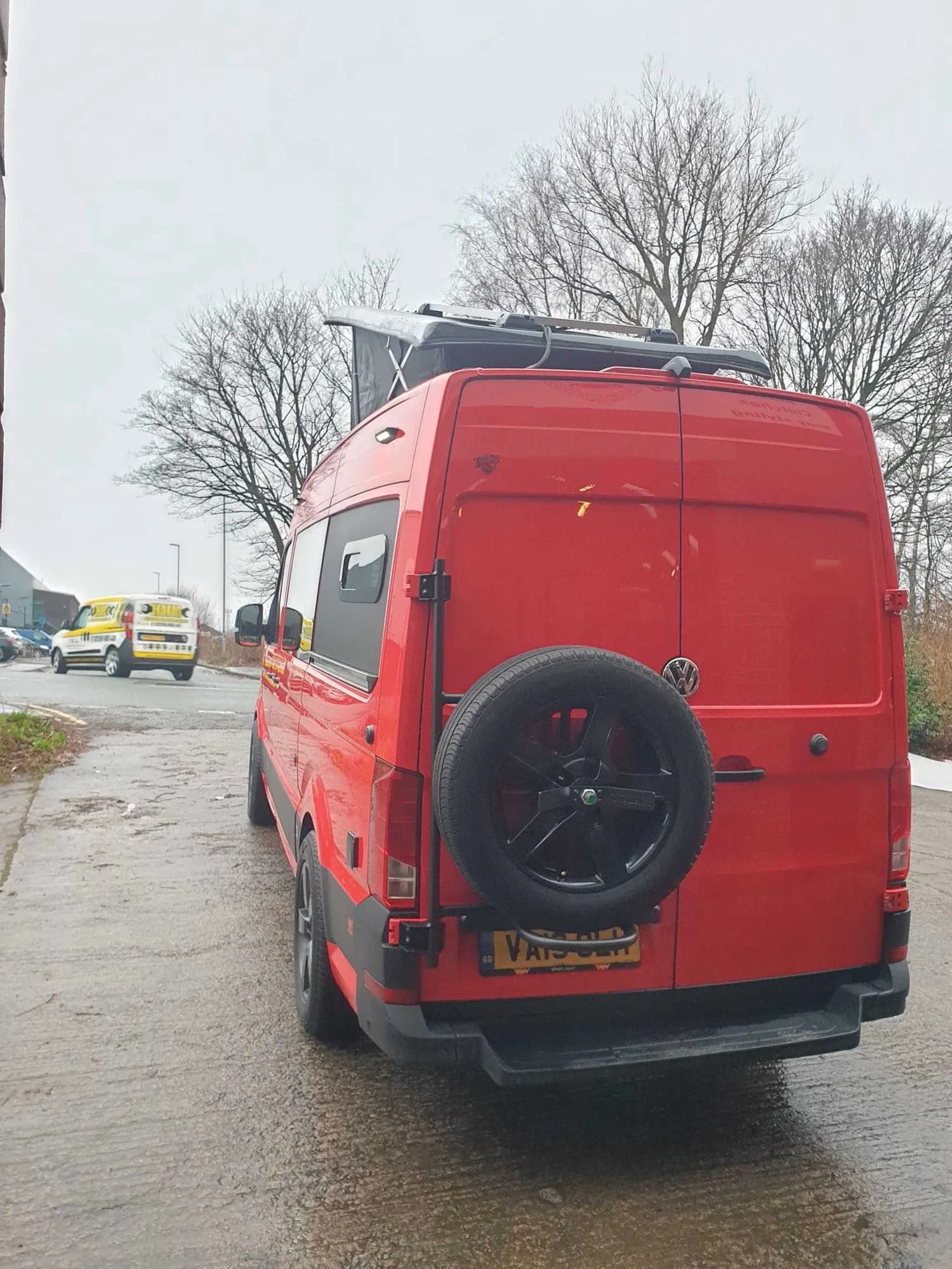Rear three-quarter view of a red VW Crafter camper with spare wheel carrier
