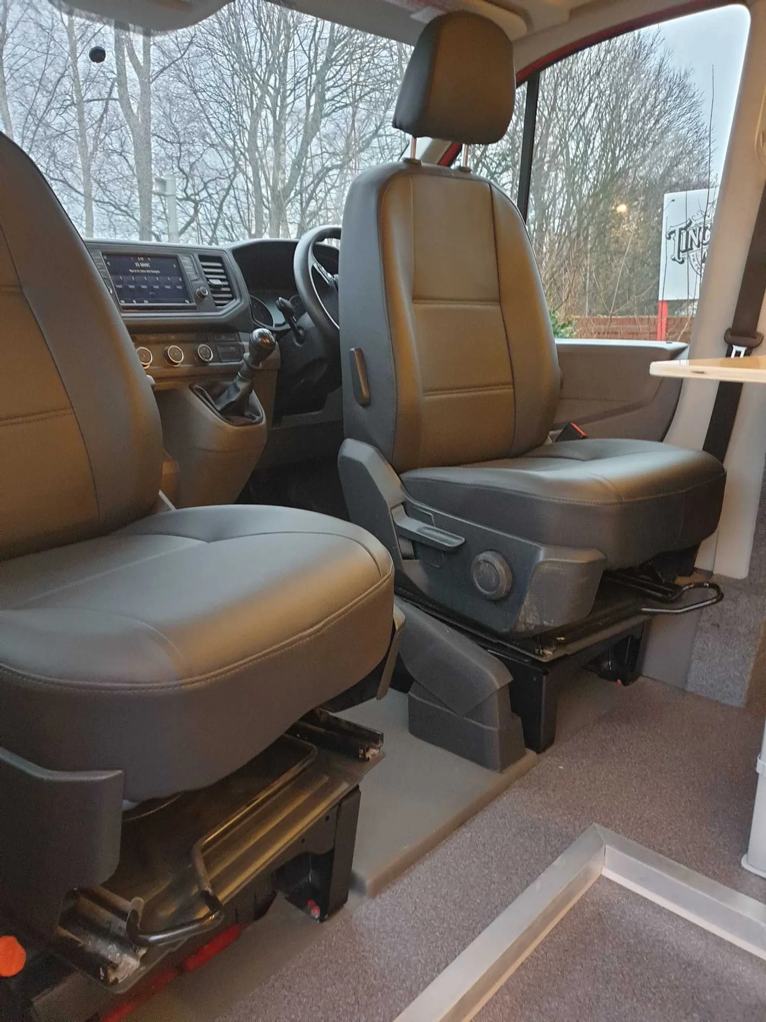 Tan leather swivel seat in the cab of a red VW Crafter conversion