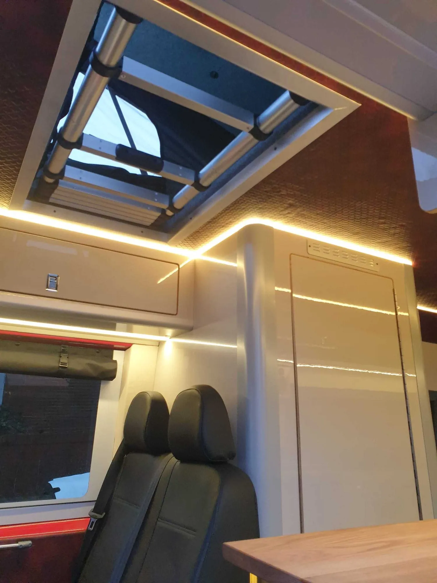 Rooflight above the seating and oak table in a VW Crafter campervan