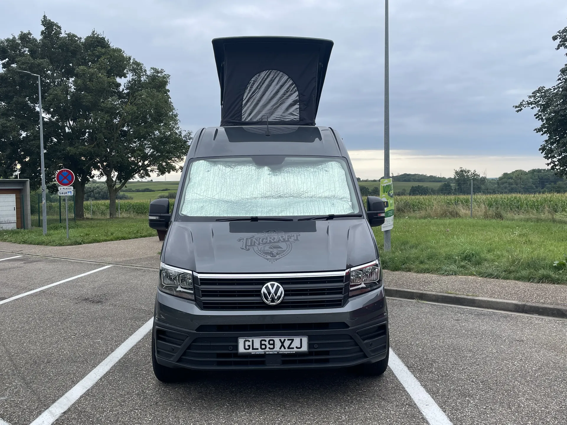 Front view of a grey VW Crafter camper with the pop-top roof raised