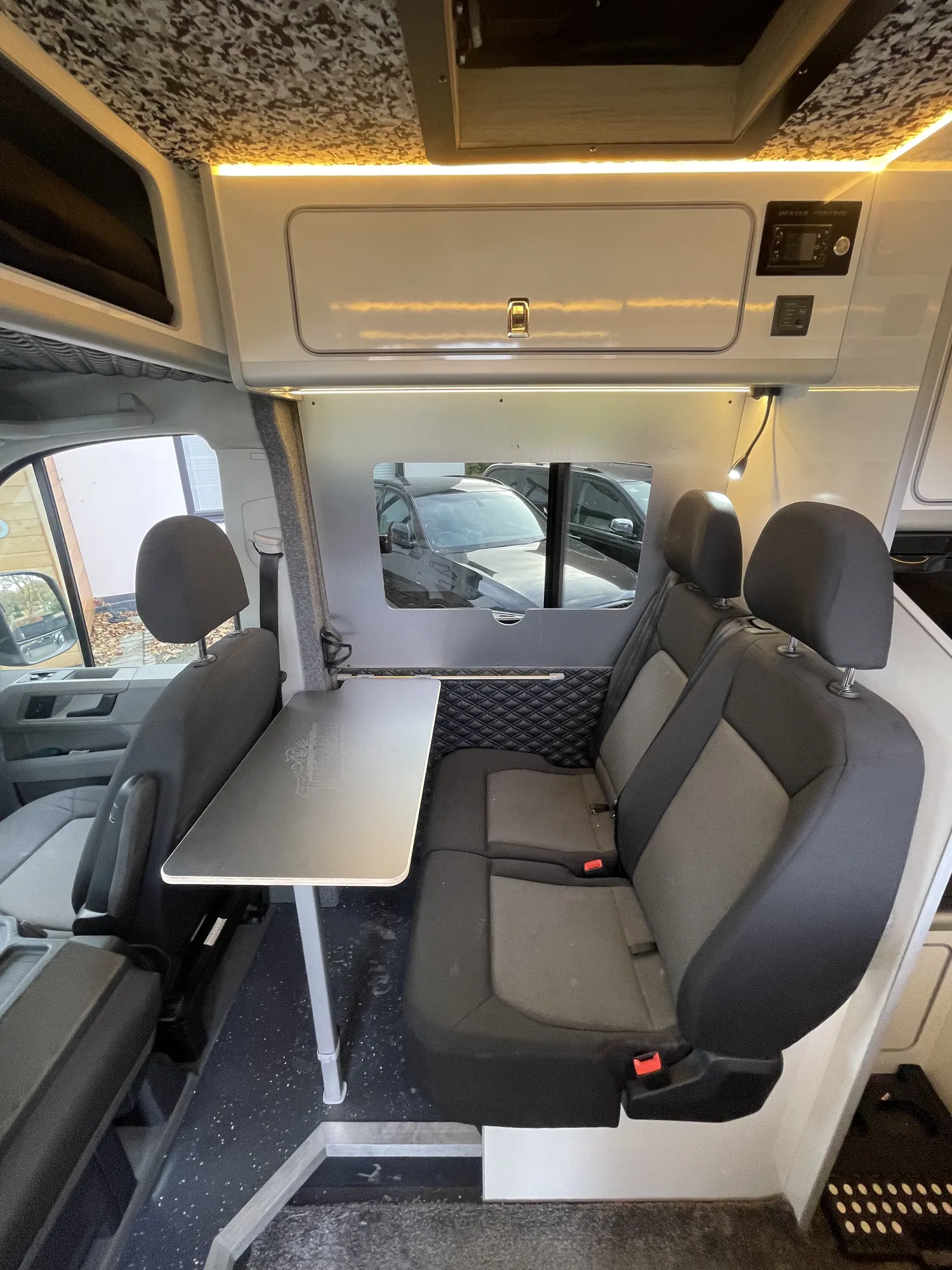 Table and swivel seats beneath a rooflight in a VW Crafter camper conversion