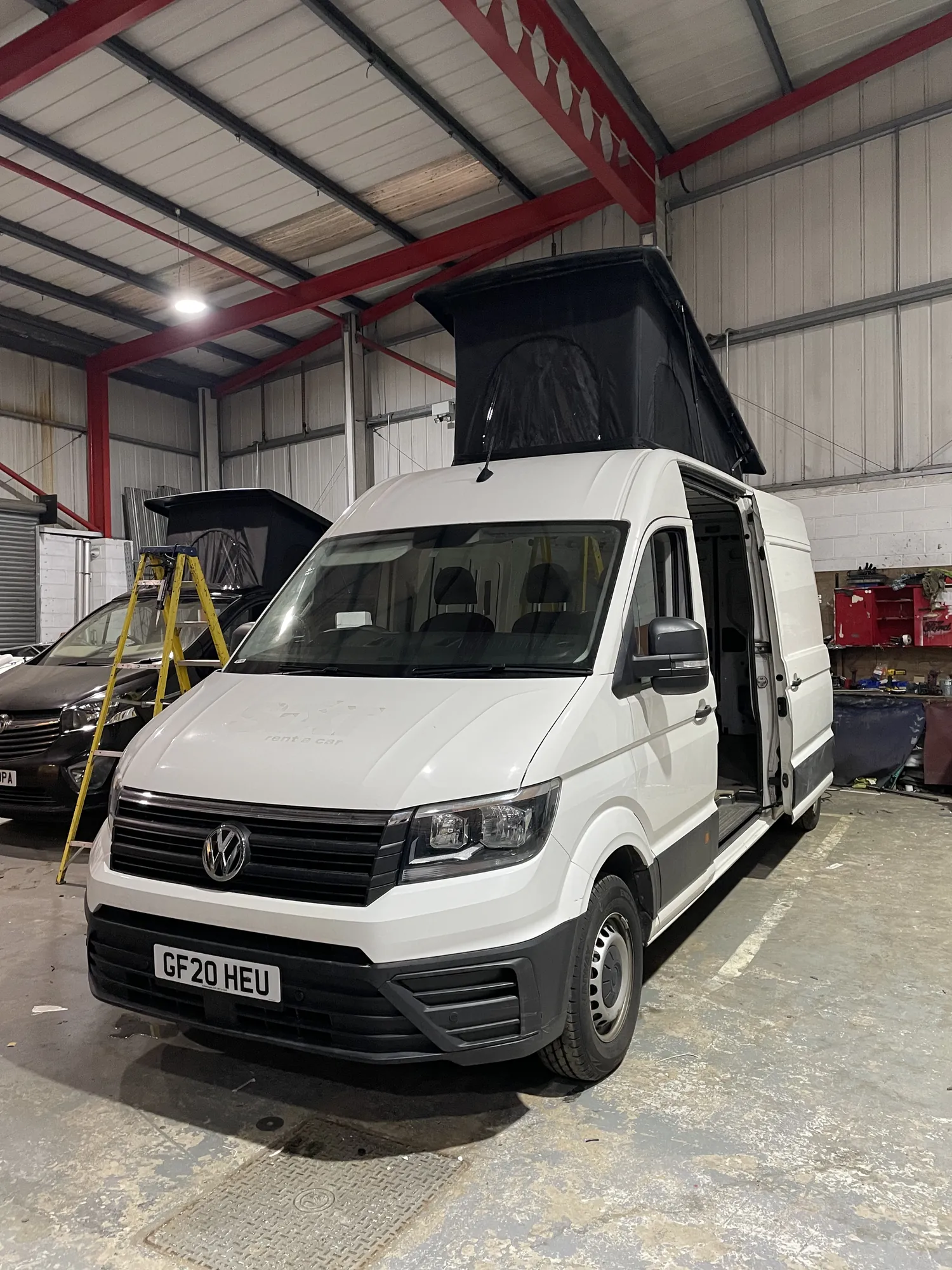 Pop-top roof raised on a white VW Crafter campervan conversion