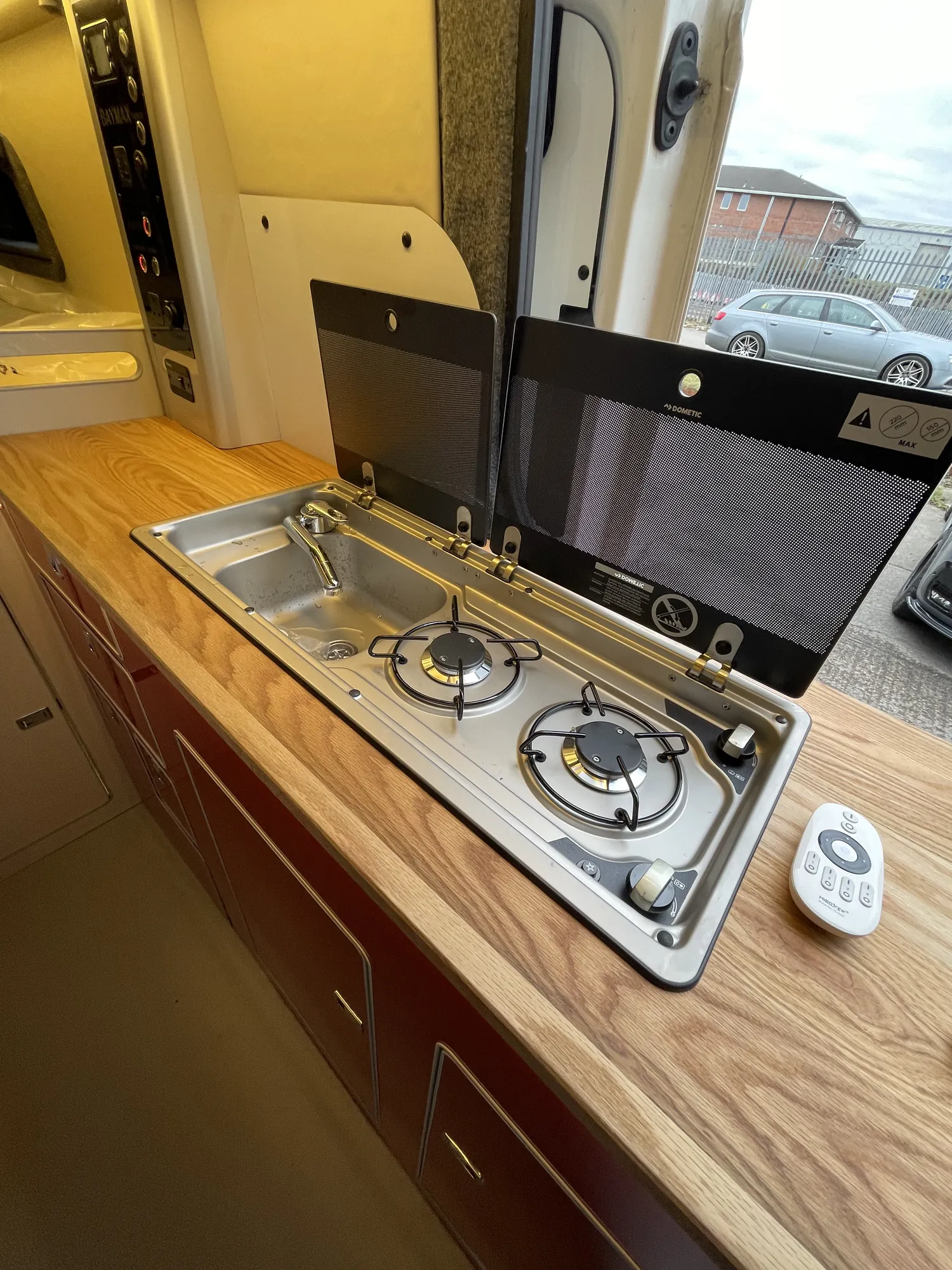 Hob and sink in an oak worktop with the lid raised in a VW Crafter conversion