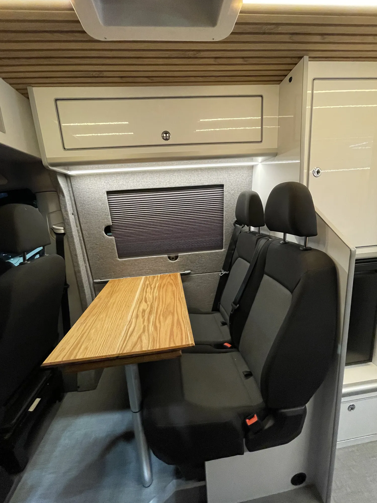 Dining table set between swivelled cab seats in a VW Crafter camper