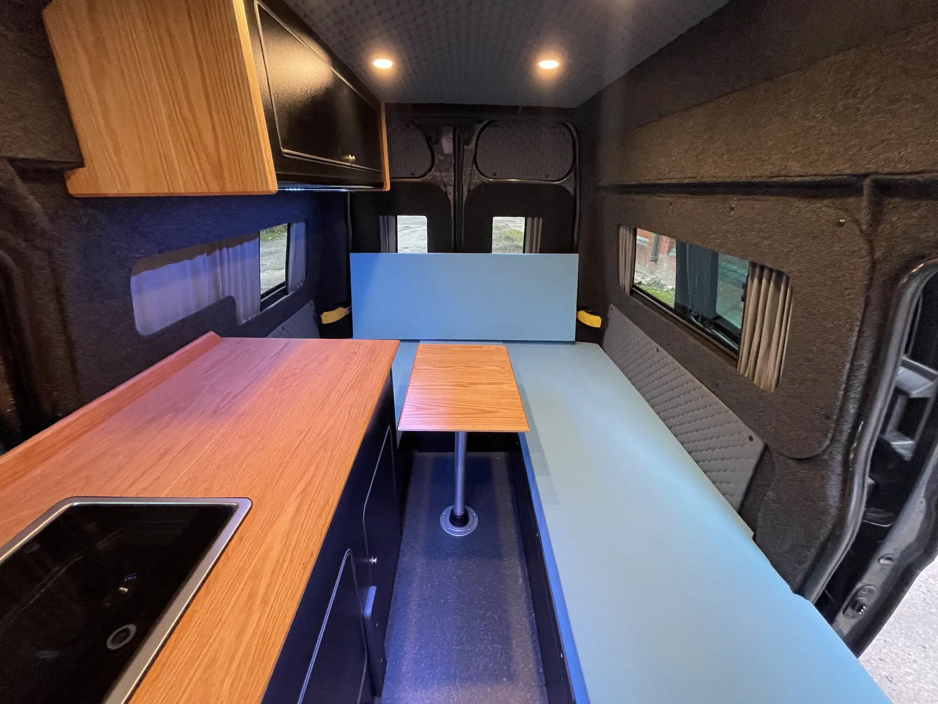 Interior of a Ford Transit Custom conversion with worktop, table and bed