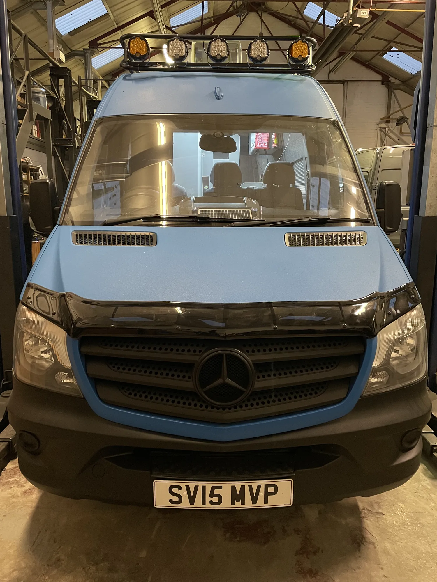 Light blue Sprinter expedition conversion with roof rack and spotlights