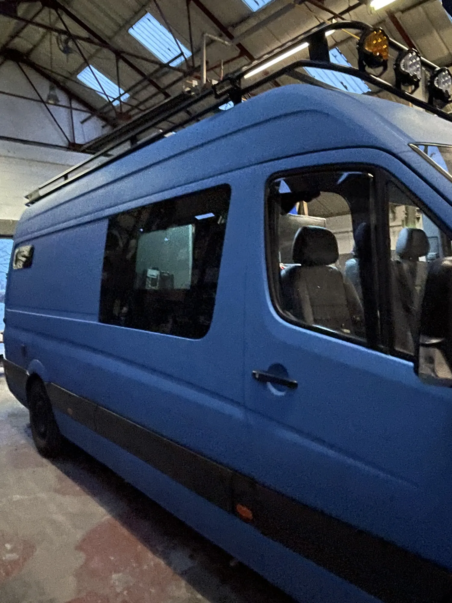 Side profile of a blue Mercedes Sprinter expedition camper with full roof rack