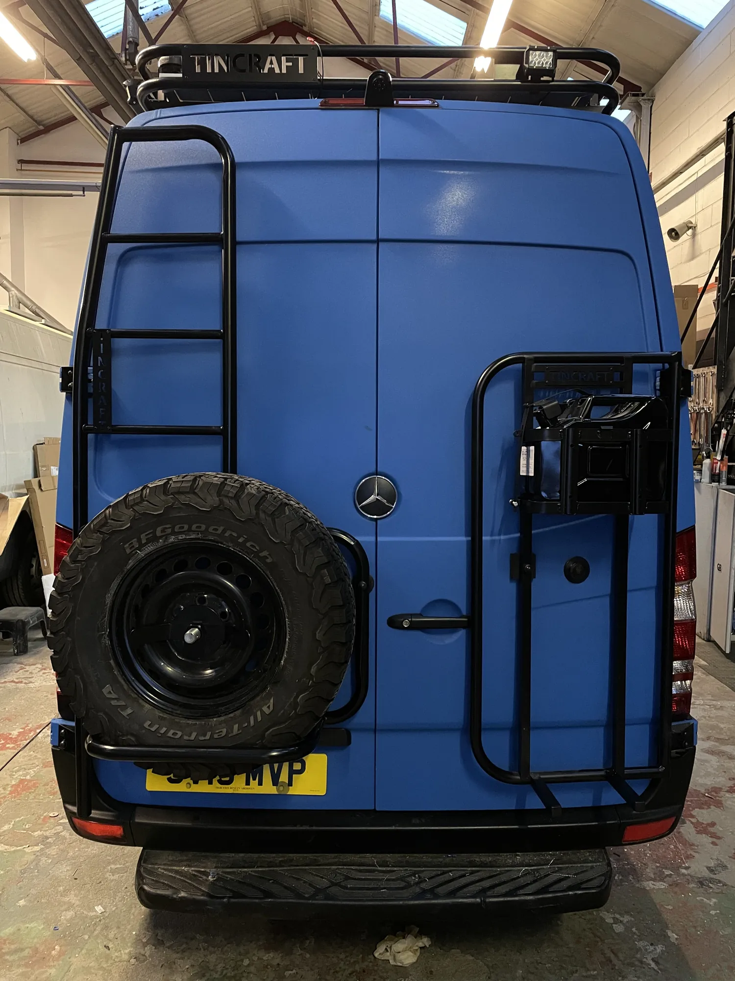 Rear of a Sprinter expedition camper with spare wheel, ladder and jerry can carrier