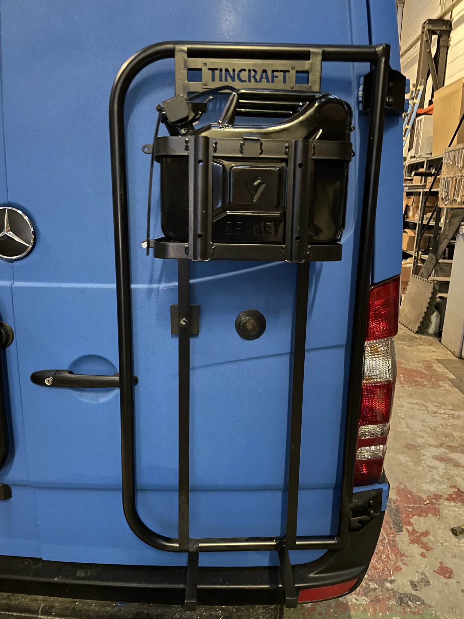 Engraved jerry can holder mounted on the rear door of a Sprinter camper